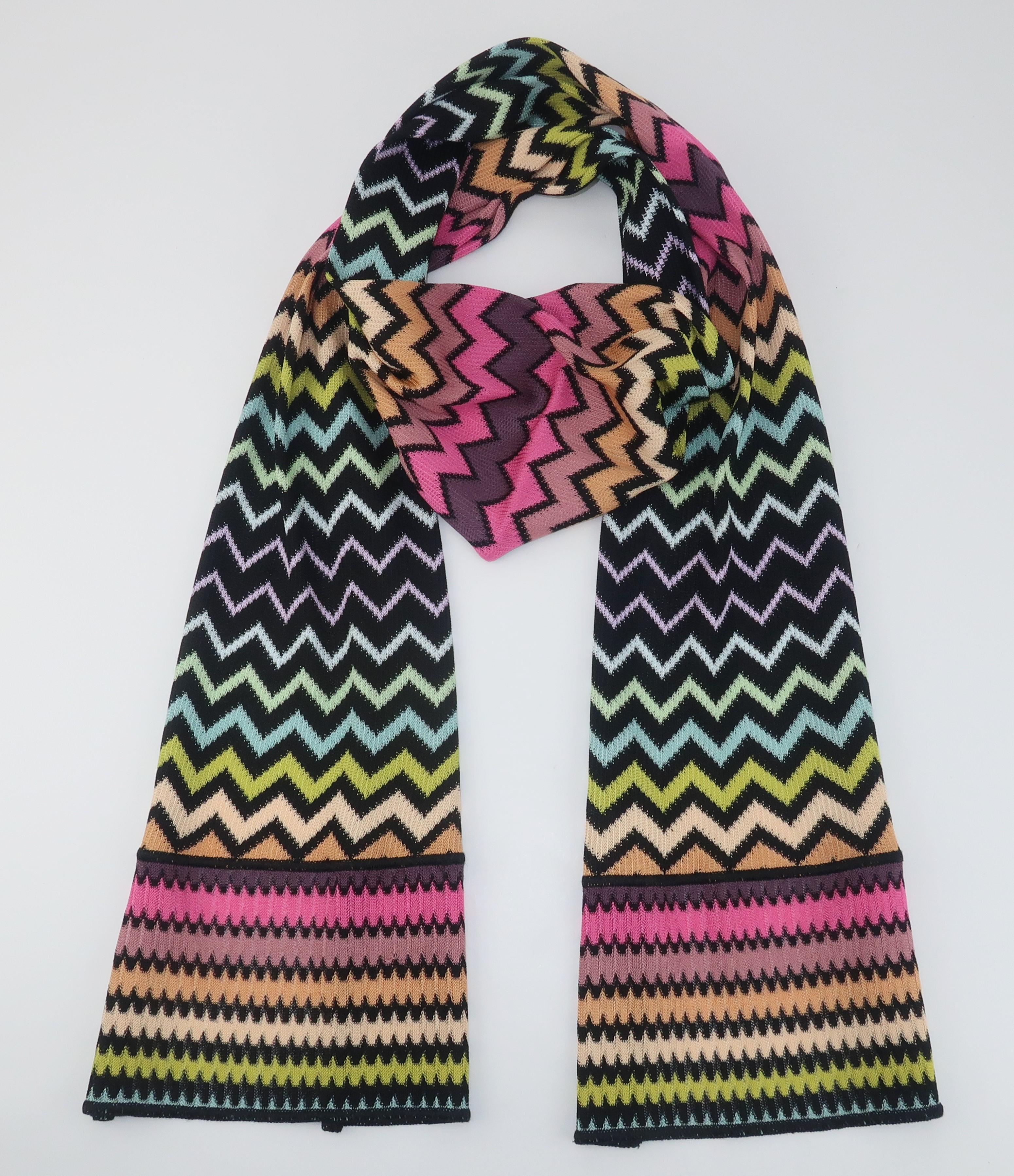 Missoni long knit scarf with the fashion brands iconic flame stitch design displaying shades ranging from peach to mauve, green, blue and hot pink all outlined in black.  Easy to drape and wear with everything from basic black to a Missoni jacket as