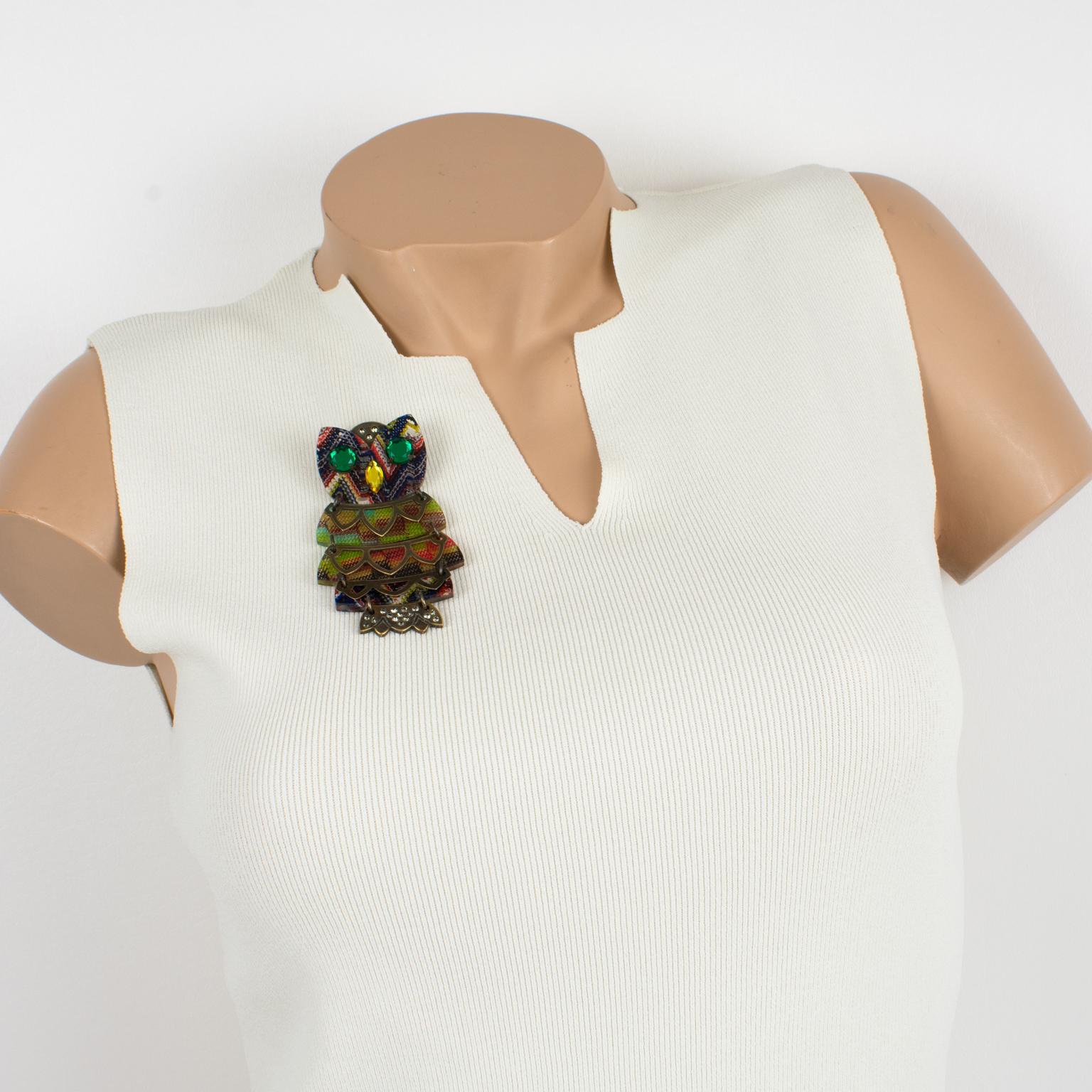 This iconic Missoni Italy pin brooch was designed in the early 2000s and features an articulated owl. The animal boasts green crystal rhinestone eyes and a yellow crystal rhinestone nose, and it is constructed from old patina brass with Lucite parts