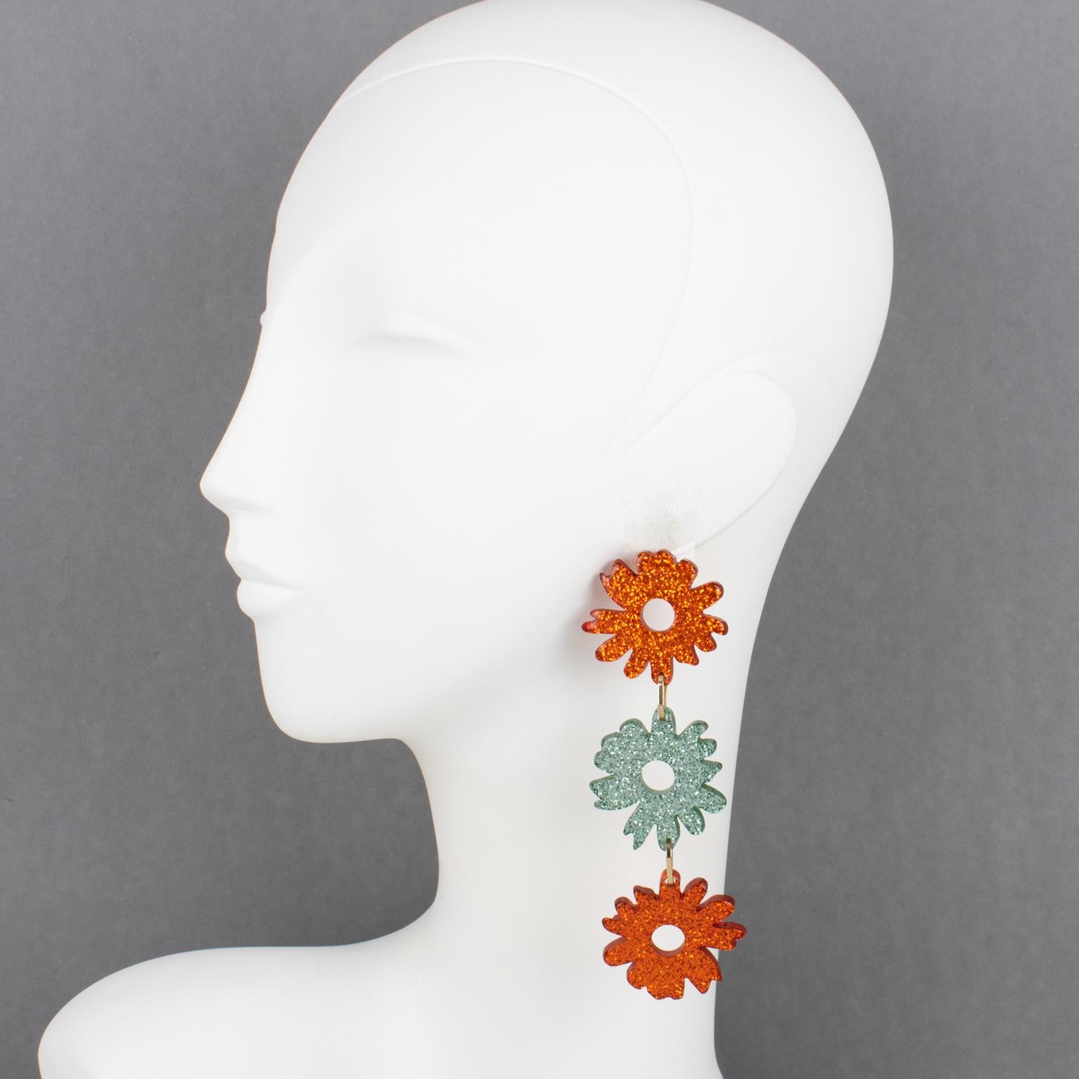 Missoni, Italy, designed these stunning oversized Lucite or resin earrings for pierced ears. The pieces feature a dangling drop shape with carved daisy flowers in an asymmetric color pattern scheme. The pieces boast burnt orange and sky blue-gray