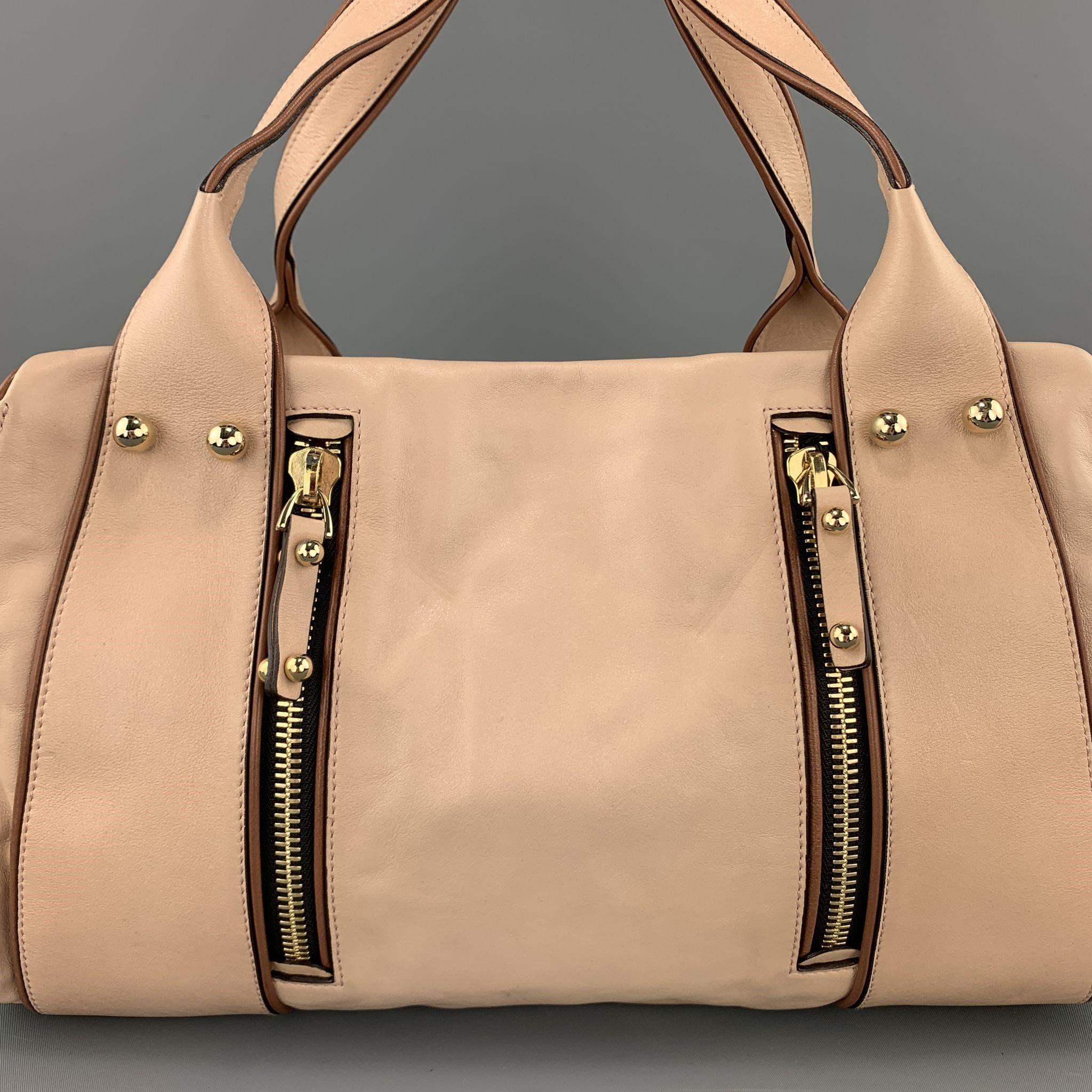 MISSONI shoulder bag comes in muted light pink smooth leather with tan leather piping, double zip pocket front, gold tone studs, double top straps, enamel side plaque, and double compartments with zip closures. Minor imperfections from storage.