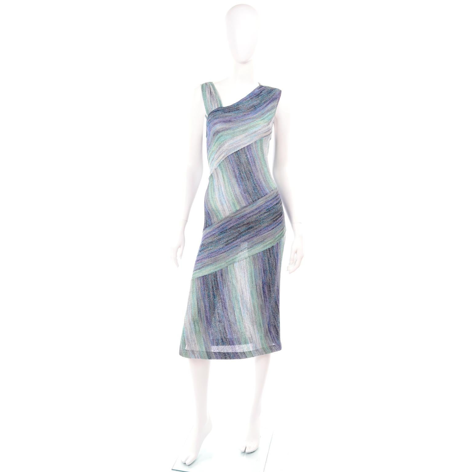 This is a very pretty Missoni metallic purple, green and blue knit dress with alternating vertical and horizontal abstract striped pattern. This dress slips overhead and has asymmetrical shoulder styling.  
Labeled an Italian size 44 and we estimate