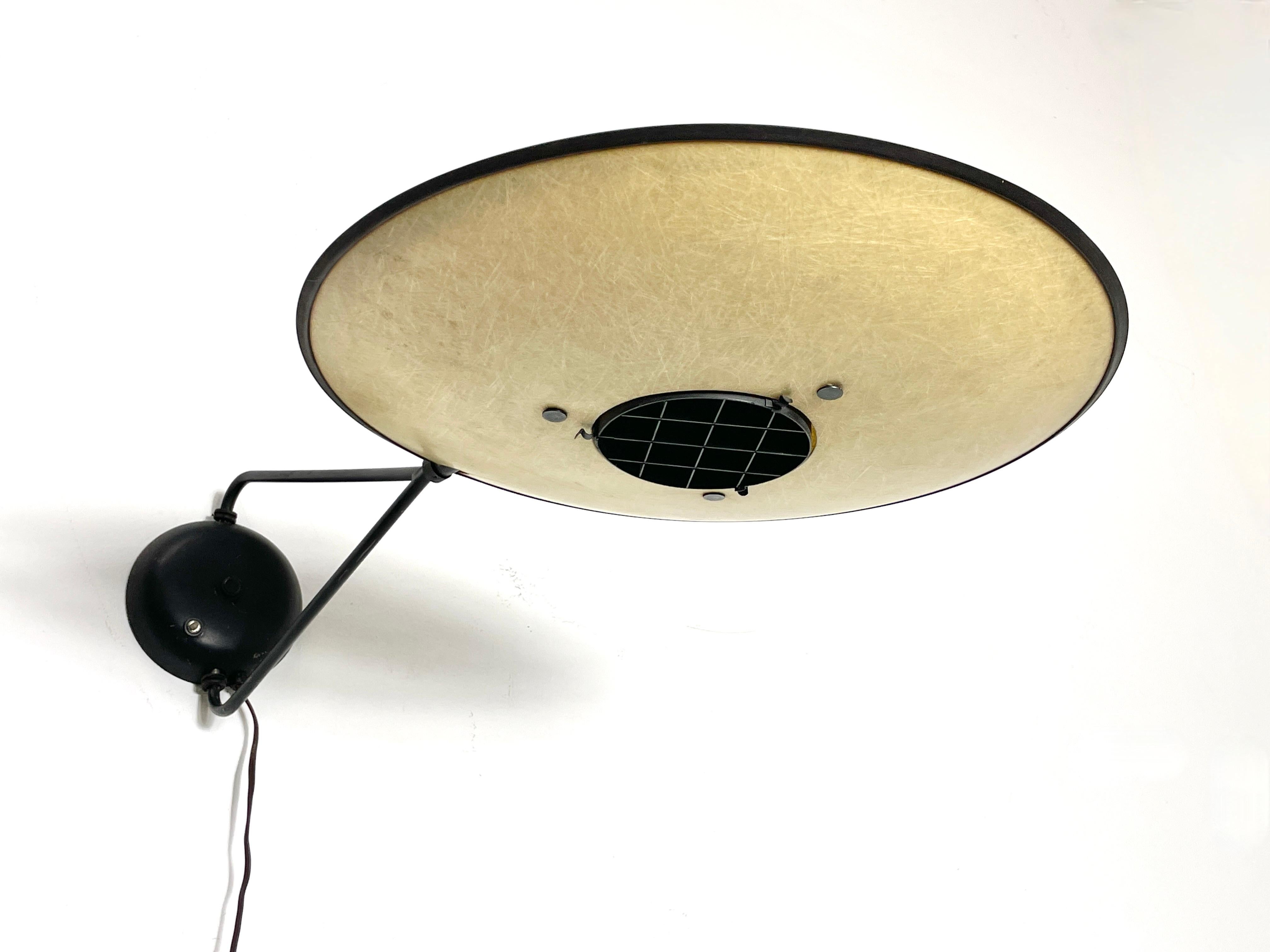 A rare wall mount Controlight lamp by Mitchell Bobrick circa late 1940s to early 1950s
Fiberglass saucer shade with black metal grid diffuser
Shade pivots on a triangular swing arm in black enameled steel
All original with label intact
