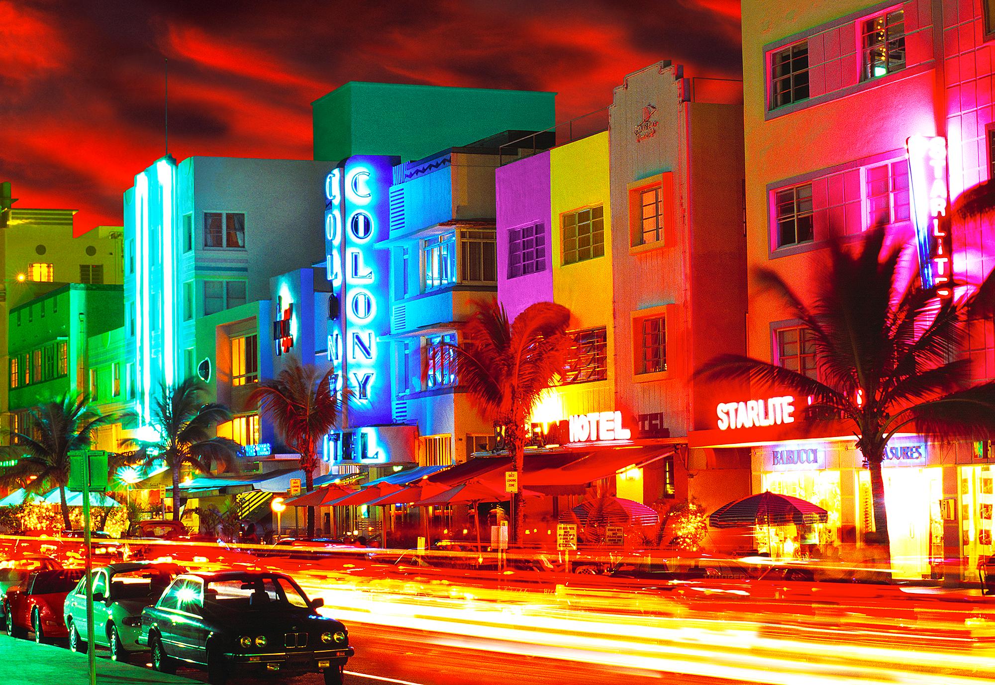 Der erfahrene Fotograf Mitchell Funk schafft ein ausdrucksstarkes Bild des Ocean Drive in Miami Beach.  Die verschwommene Farbe, der knallrote Himmel und die blutenden Art-Déco-Neonschilder sind die visuelle Entsprechung dessen, was South Beach