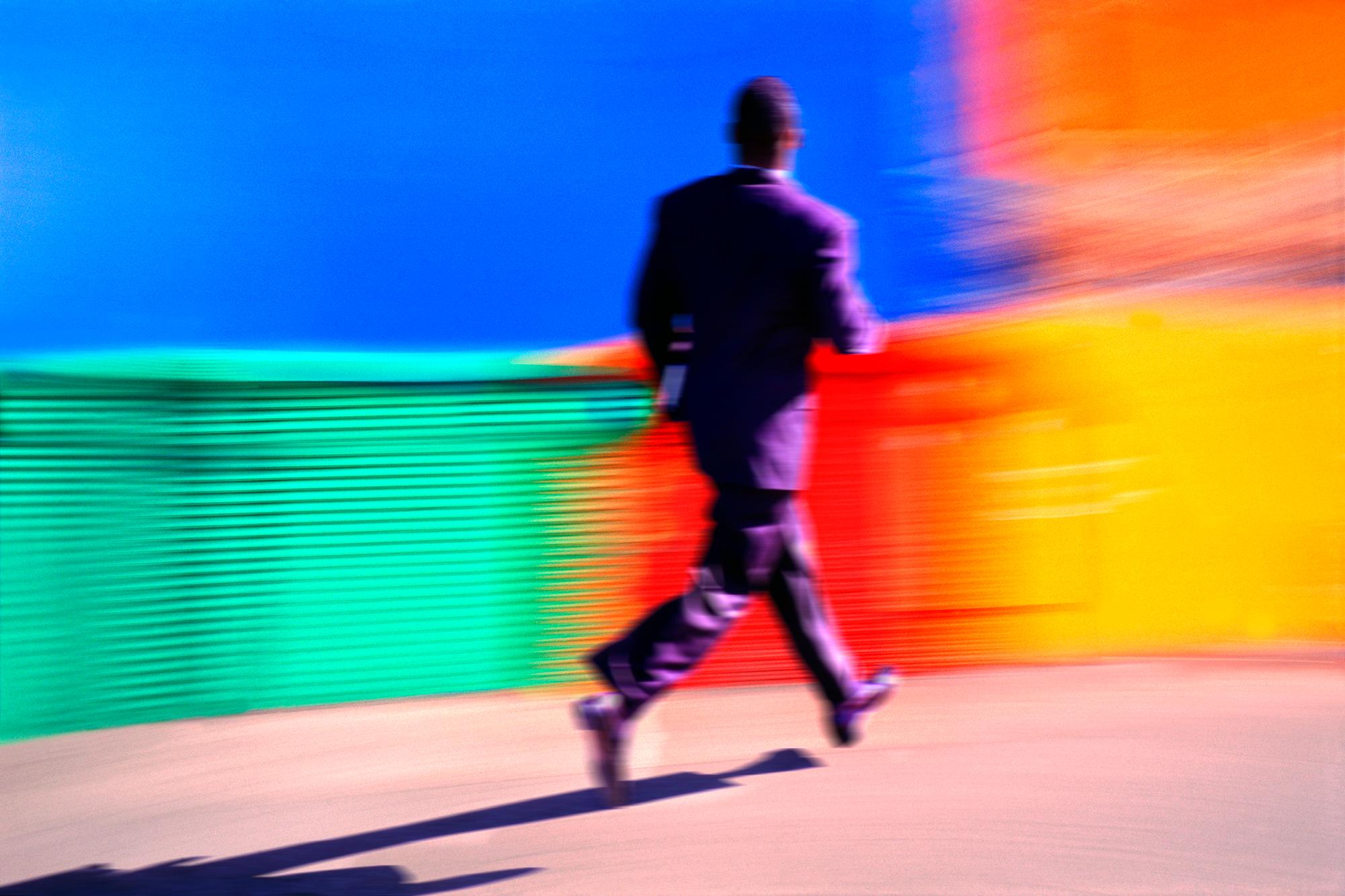 Mitchell Funk Color Photograph - Black Businessman Running Against a Colorful Background