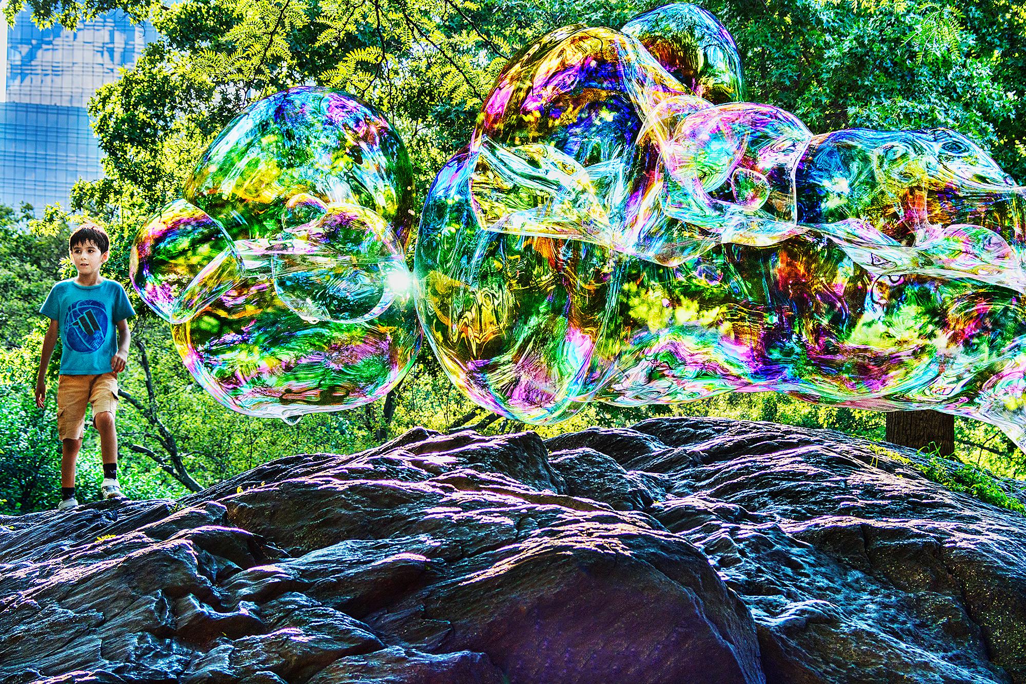 Mitchell Funk Abstract Photograph – Junge spielt mit Blasen im Central Park 