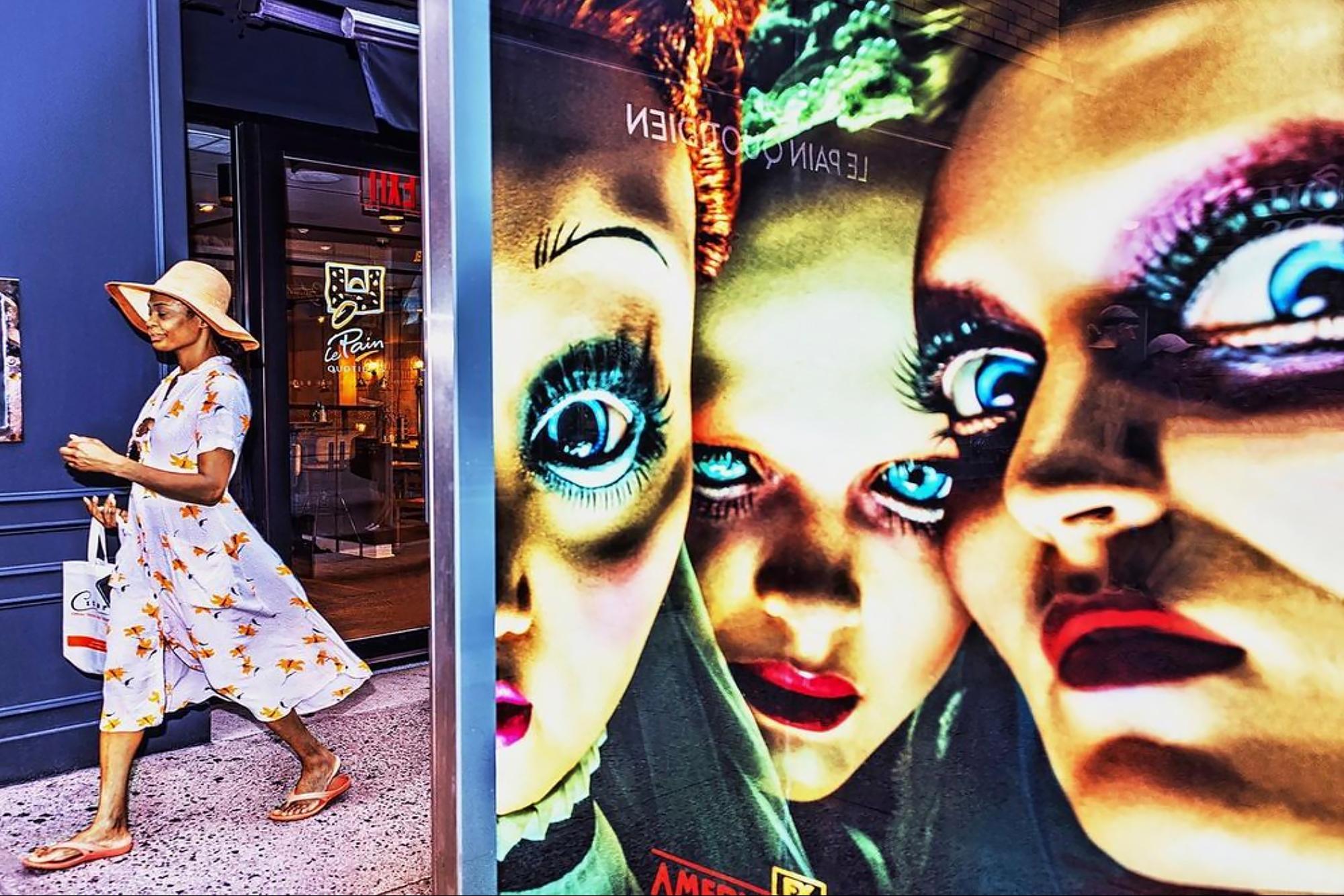 Mitchell Funk Figurative Photograph - Double-take.  Street Photography with Eerie Blue Eyed Billboard