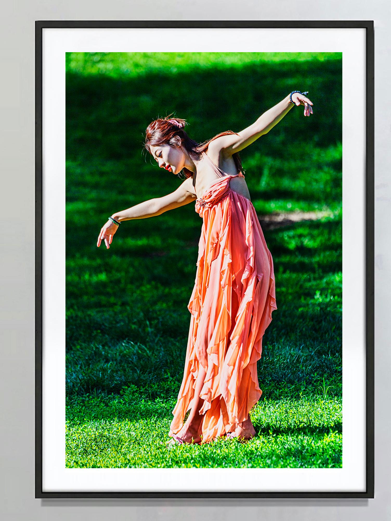 Free Spirited Asian Female Dancing Outdoors against Green Background - Photograph by Mitchell Funk