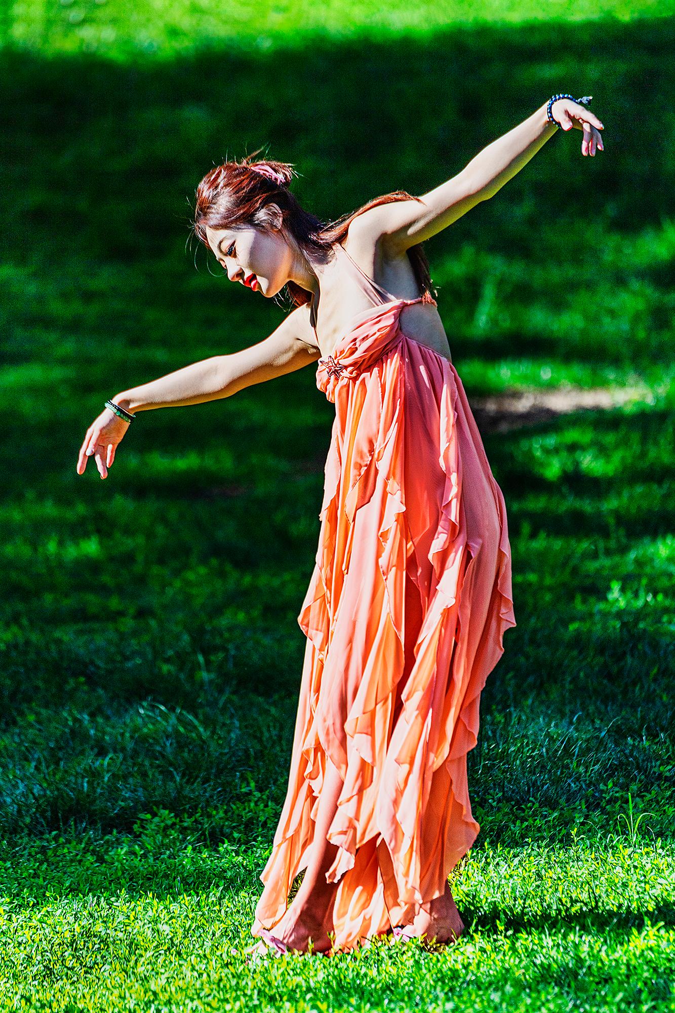 Mitchell Funk Color Photograph - Free Spirited Asian Female Dancing Outdoors against Green Background