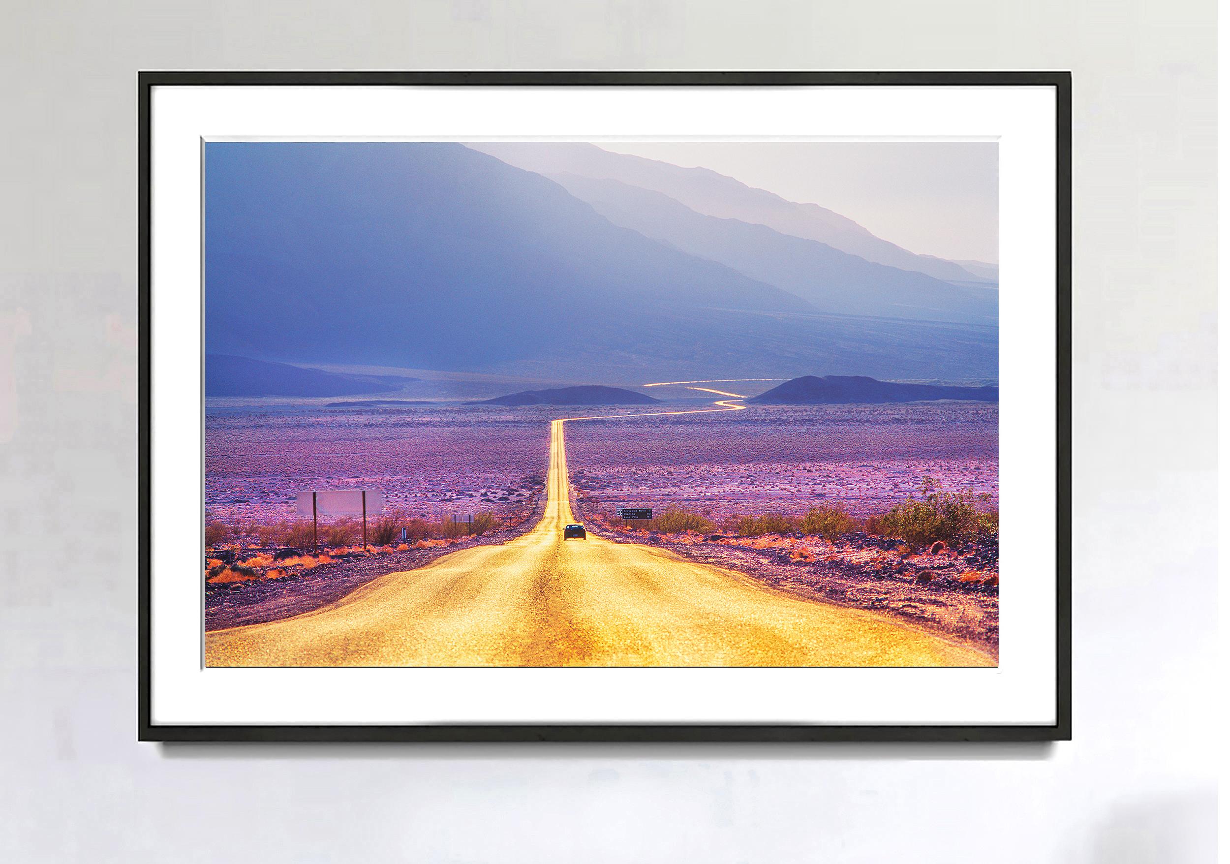 Man is dwarfed by nature. A long golden road winds through the vast expanses and monumentality of the American West. The grandeur of the surrounding landscape minimizes a single car; the warm color scheme of the road seamlessly integrates with