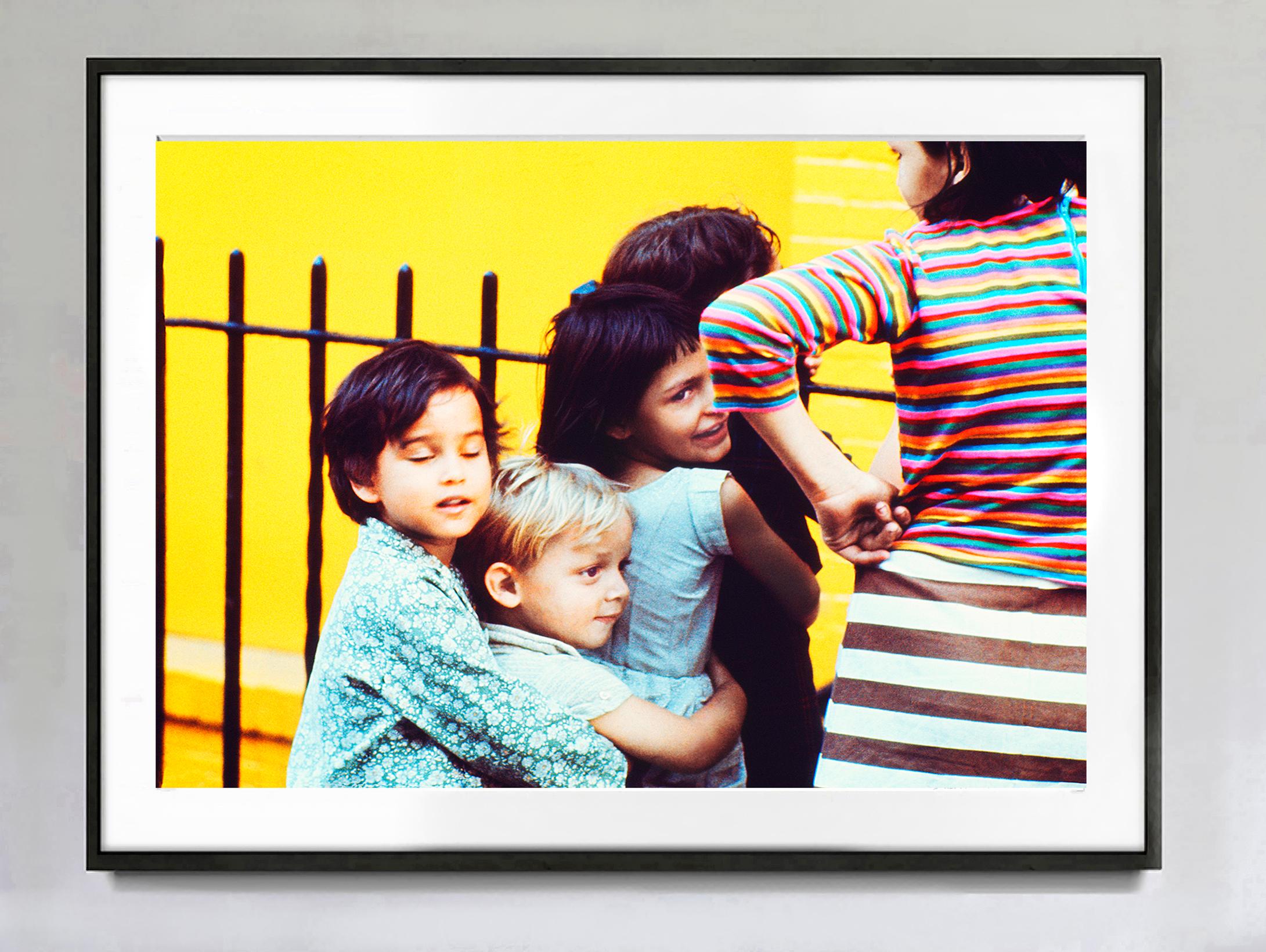 Kinder haben Spaß vor der gelben East Village-Wand, Straßenfotografie in Farbe  – Photograph von Mitchell Funk