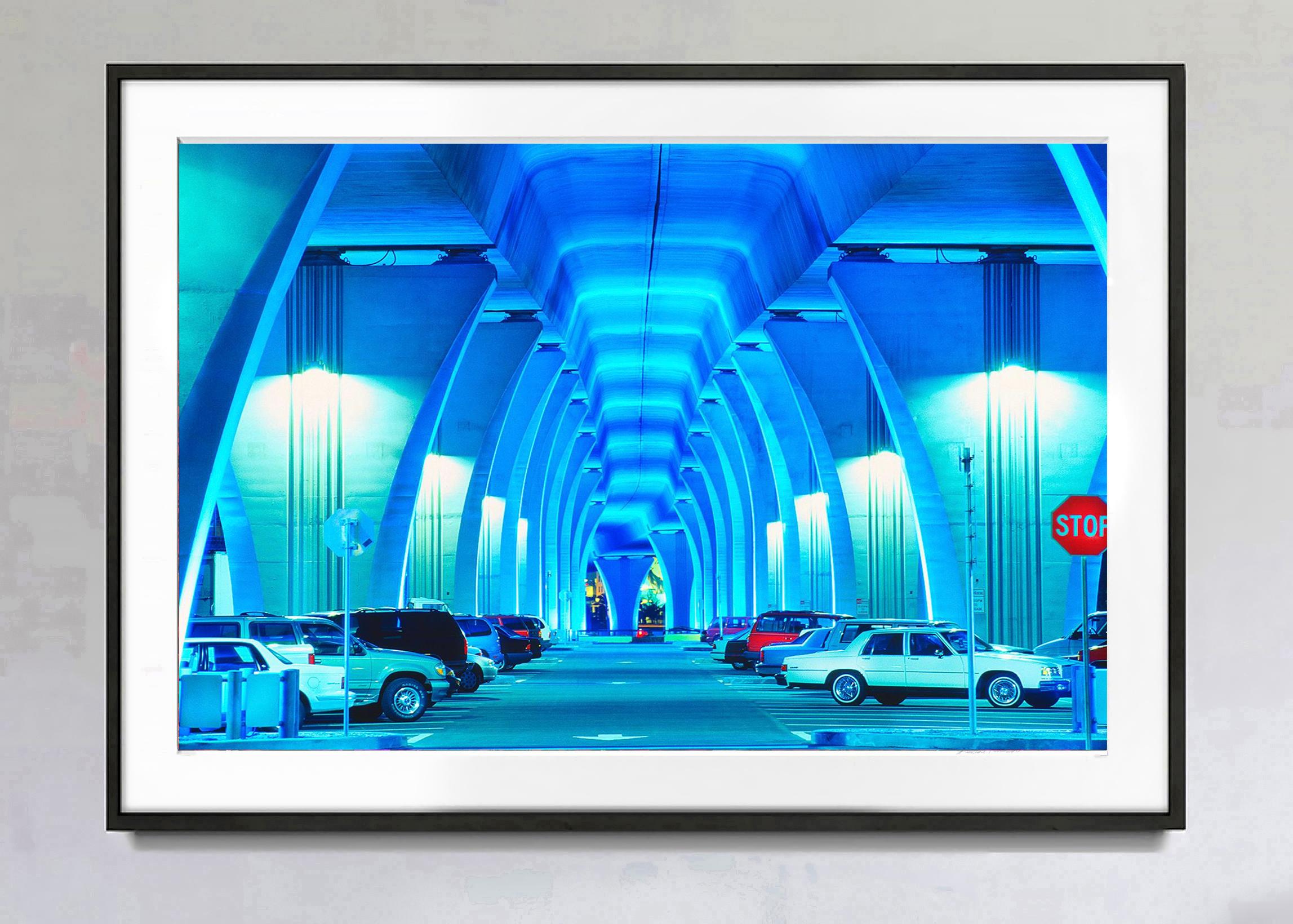 The underside of a blue bridge in Miami is transformed into a statement of about urban color. It's a hauntingly beautiful night image of Miami in blue and is punctuated with a red stop sign.  Signed and dated on the lower right, numbered on verso,