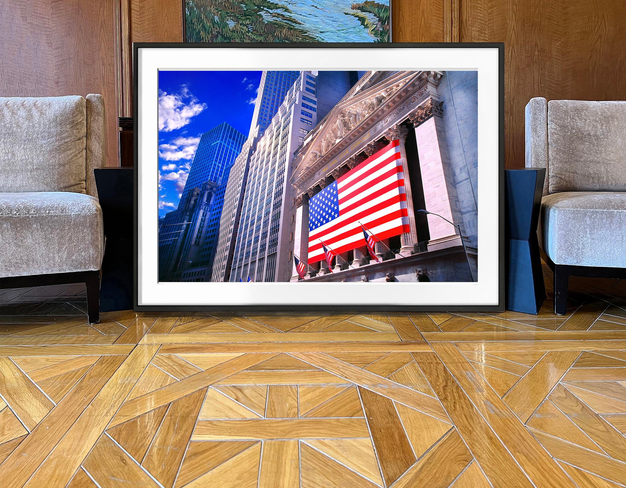 The symbol of American Capitalism is cloaked in the symbol of American Freedom.  A monumental American Flag drapes the shiny facade of the New York Stock Exchange.  Bright light illuminates the scene, adding to a sense of buoyant optimism.  The