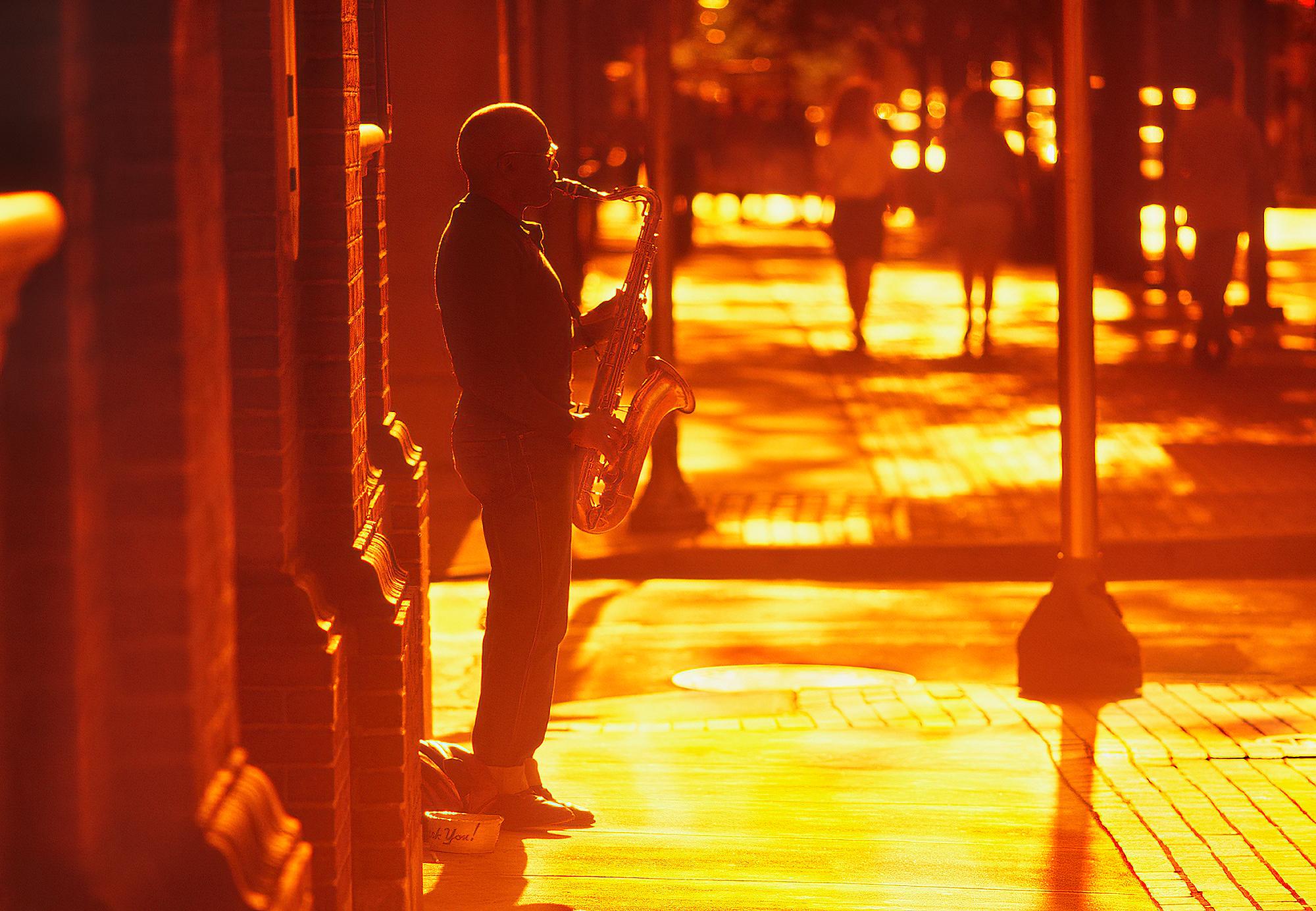 Mitchell Funk Landscape Photograph - Romantic Street Musician Playing the Saxophone in Golden Light and Orange