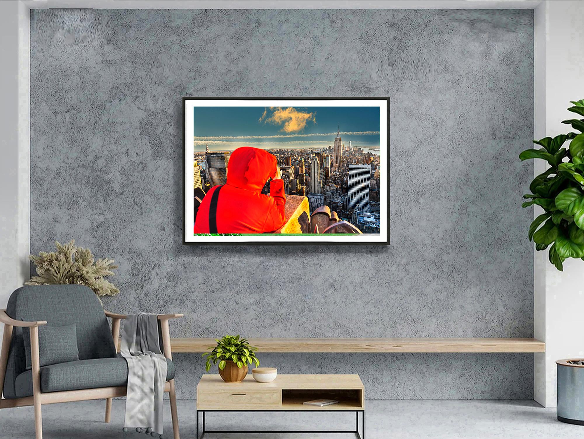 Una vista despejada del Bajo Manhattan desde la plataforma de observación de 30 Rock se ve obstruida por una figura con una sólida chaqueta roja con capucha.  La figura se convierte en una forma abstracta dominante en la composición.  Ése es el
