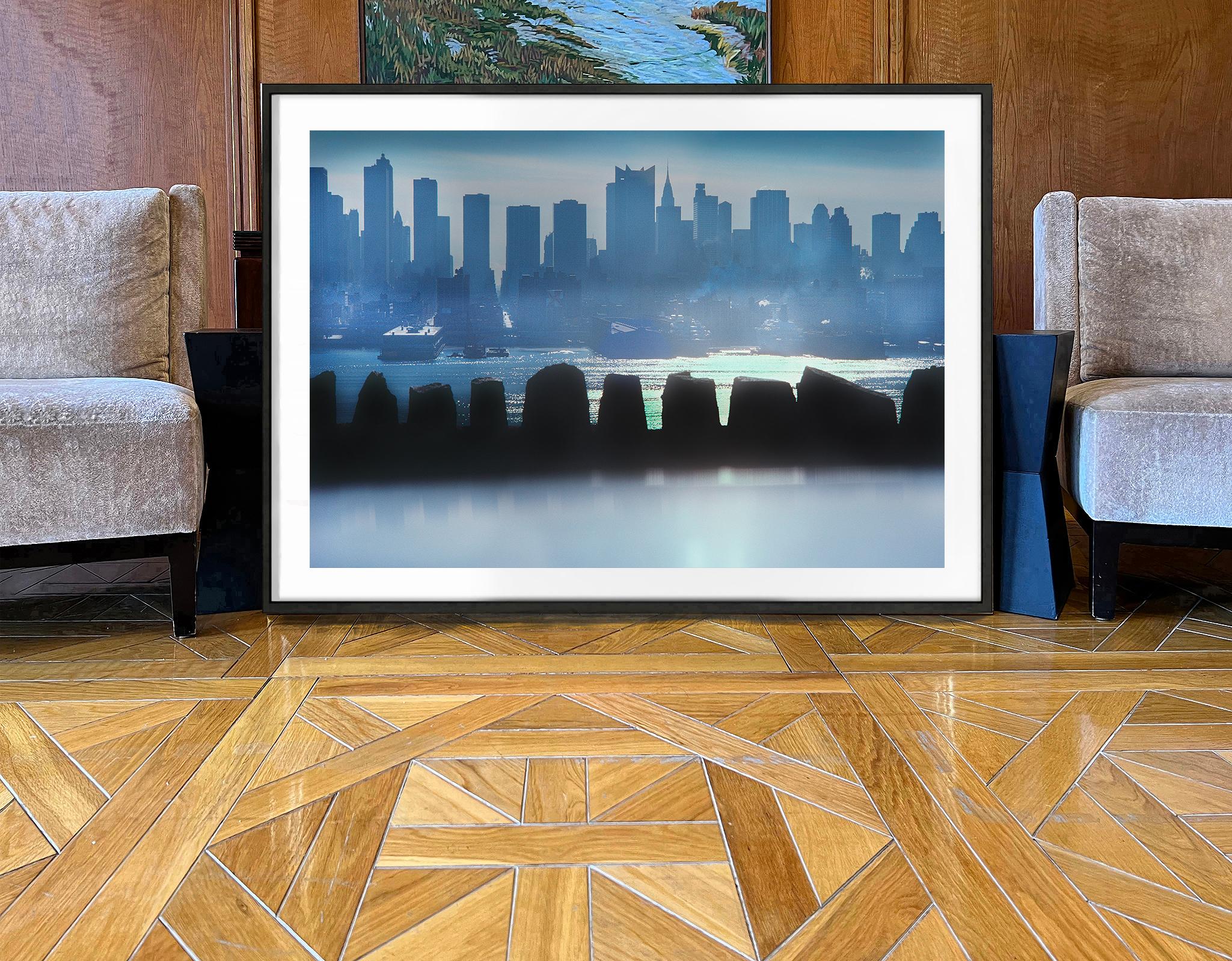 A foreground stone wall structure of a repeating vertical shapes alternating with openings is mimicked by the similar but more majestic vertical shapes of the Mid-Town Manhattan skyline. It was photographed early in the morning, so the backlit