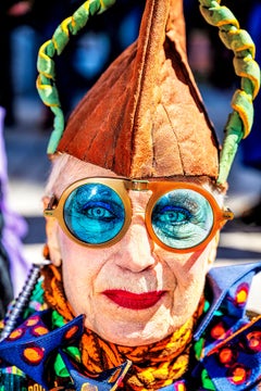 Skurrile Frau mit farbenfrohem, phantasievollem Outfit und blauen Augenbrille