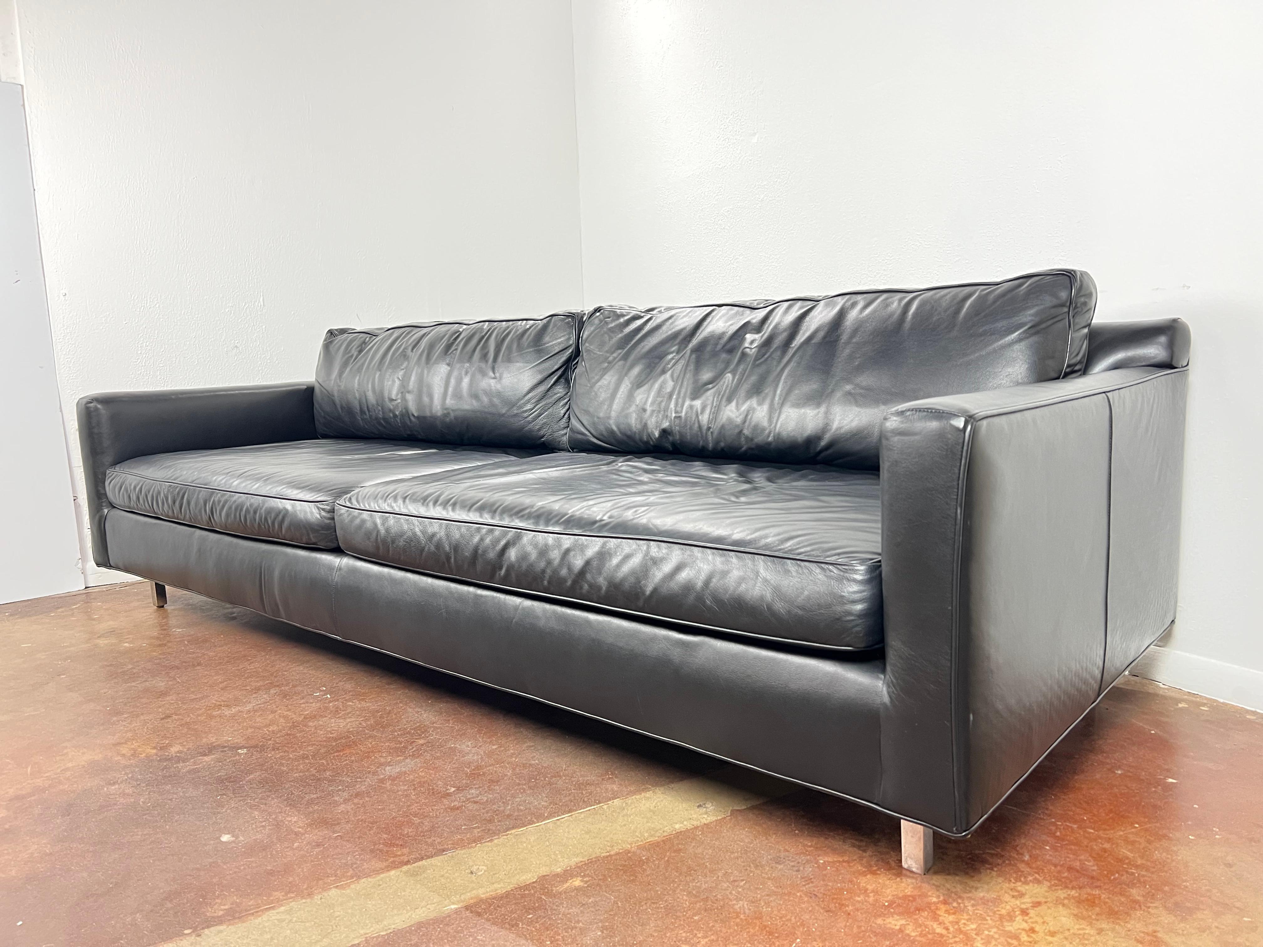 Low and luxe modern sofa in specially treated black performance Italian leather from Mitchell Gold + Bob Williams. Lush seat and back cushions make it especially comfortable. Square polished stainless steel legs. Sinuous wire spring suspension and