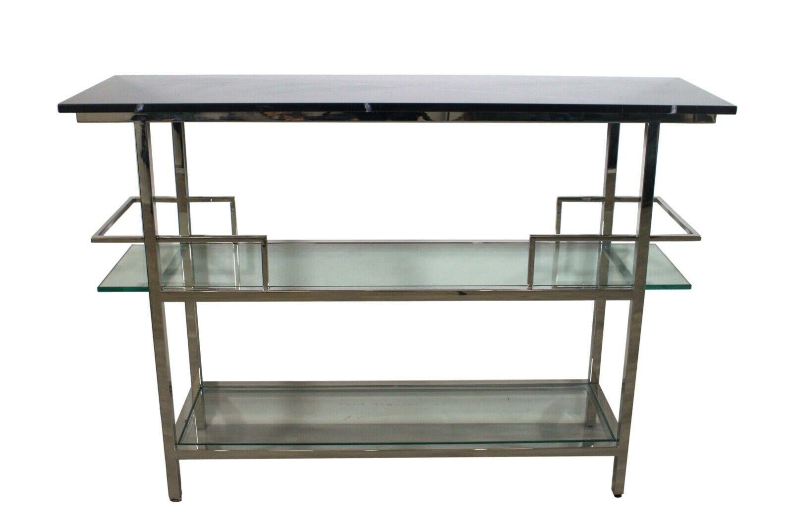 The Mitchell Gold + Bob Williams Modern Chrome, marble, & glass three tier bar cart is the perfect statement piece for your home. This chic and stylish cart features a glossy chrome frame with mirrored glass shelves, combined with a black marble top