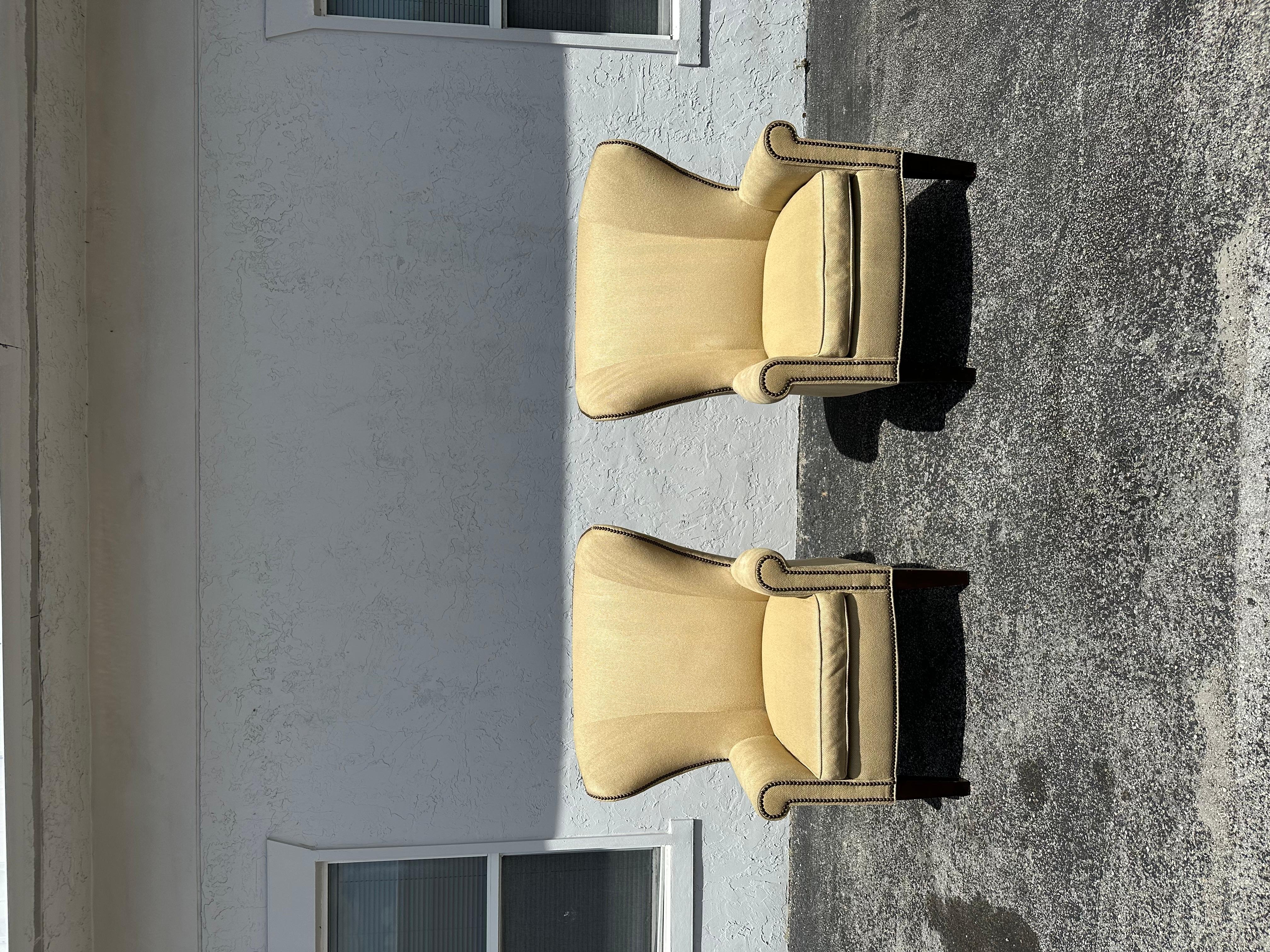 Pareja de sillas con respaldo de Mitchell Gold + Bob Williams. Las sillas están tapizadas en una chenilla neutra con textura de espiga. Las patas de madera son cuadradas y cónicas, con acabado negro. Las cabezas de clavo acentúan el faldón delantero