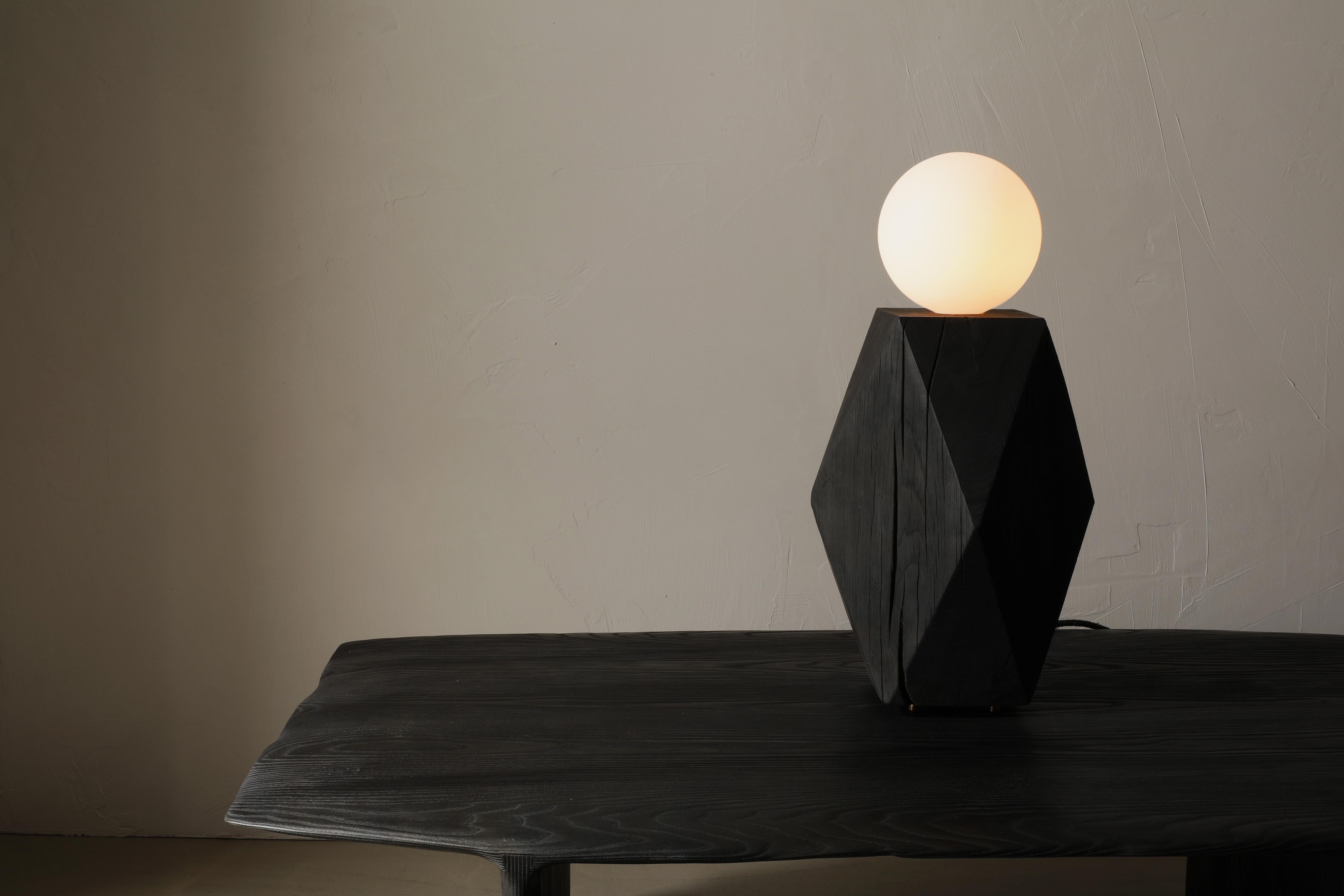 The Miter Lamp is a solid oak table lamp with a large frosted globe bulb. The lamp sits on four bronze feet and is switched on the cord with a dimmer.

The MITER Collection – a sustainable transformation from recycled wood beams to refined