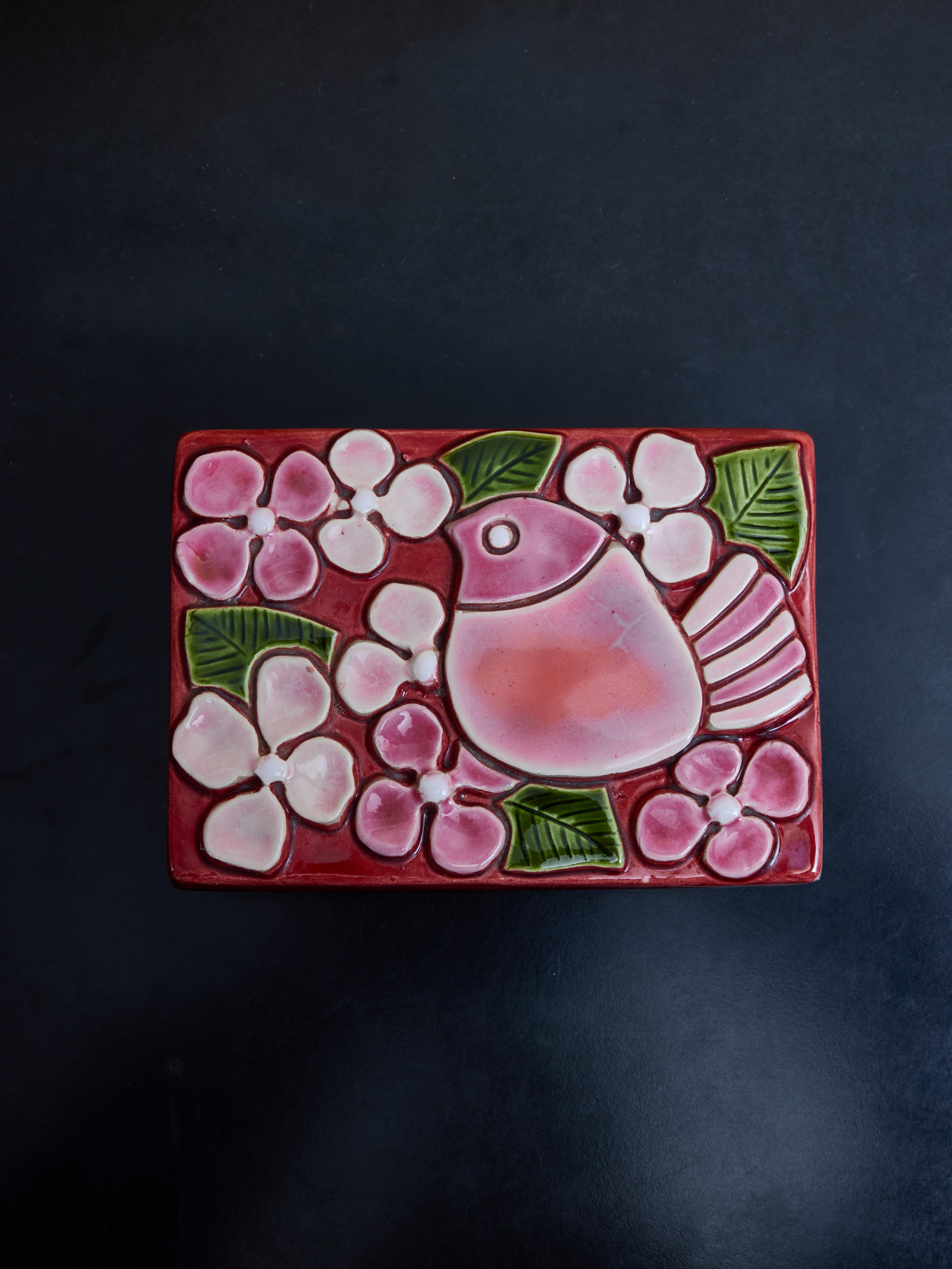 Rectangular wood box topped with a ceramic lid glazed in different red and pink hues with green accent with a bird with flower decor, made by Mithé Espelt.

Marie Thérèse Espelt, aka. Mithé Espelt (1923-2020)

Born in the town of Lunel, near
