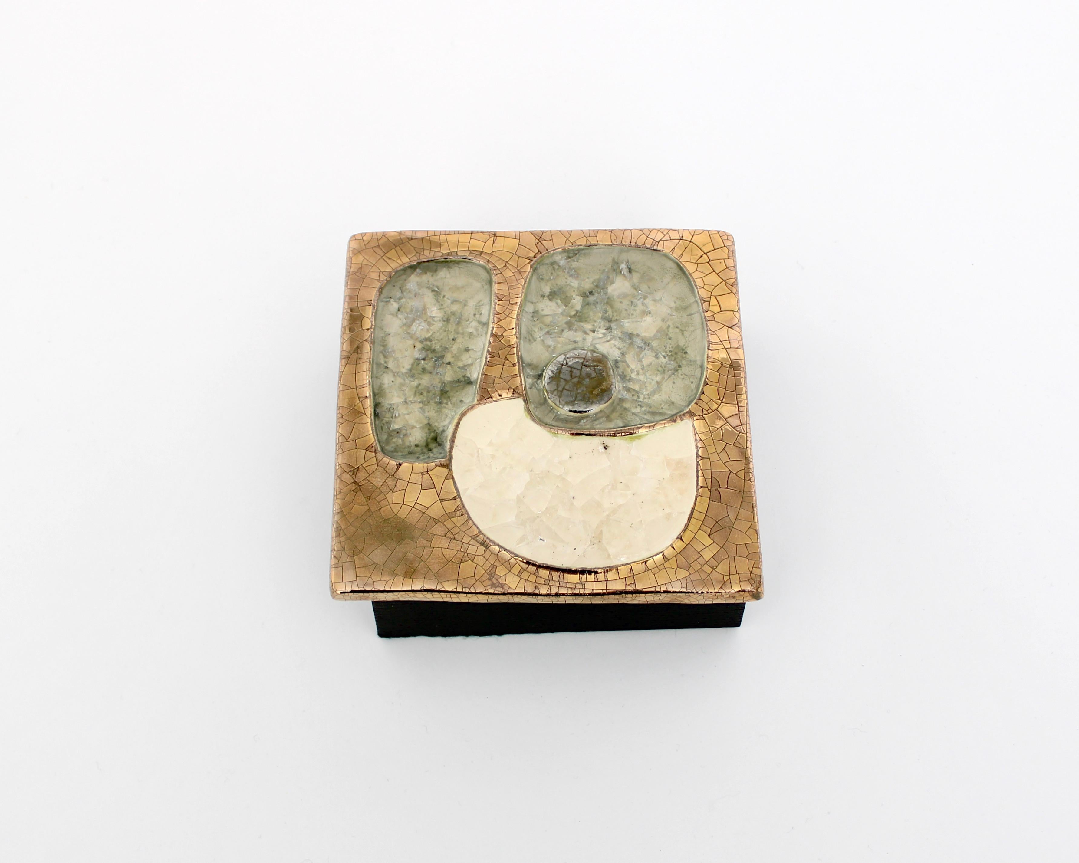 Boîte à bijoux en céramique par Mithé Espelt, France, années 1960 Émaux en céramique dans des tons d'or avec du verre fusionné de couleur crème et bleu pâle vert de mer avec une boîte en bois noirci iconique. 
Littérature : Mithé Espelt, le luxe