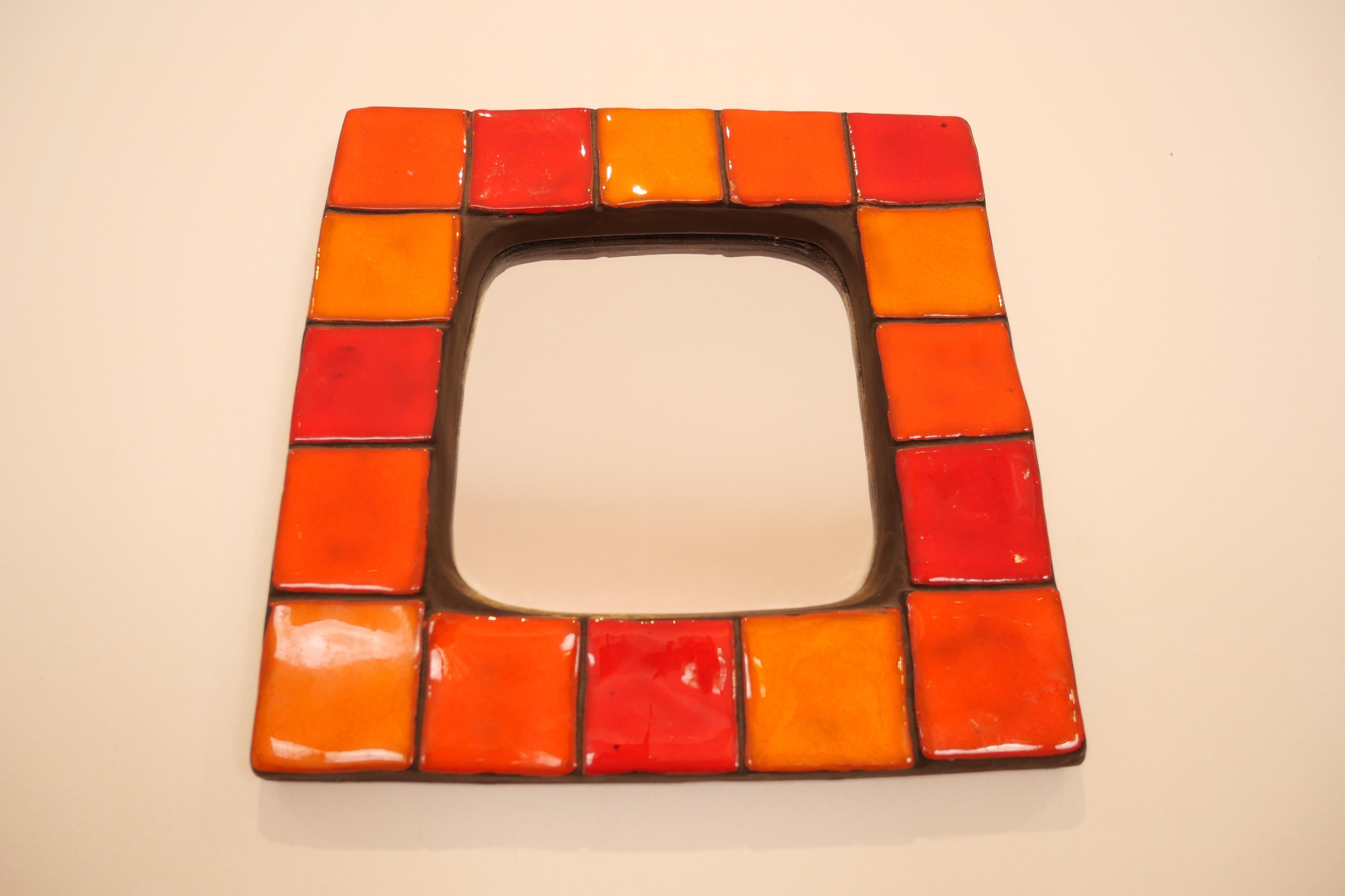 Mithe Espelt square ceramic mirror enameled in various shades of red and orange ceramic, France, 1970s.
In good original condition with felt green backing. 

Mithé Espelt born in 1923 is a French ceramist based in Camargue, South of France. At