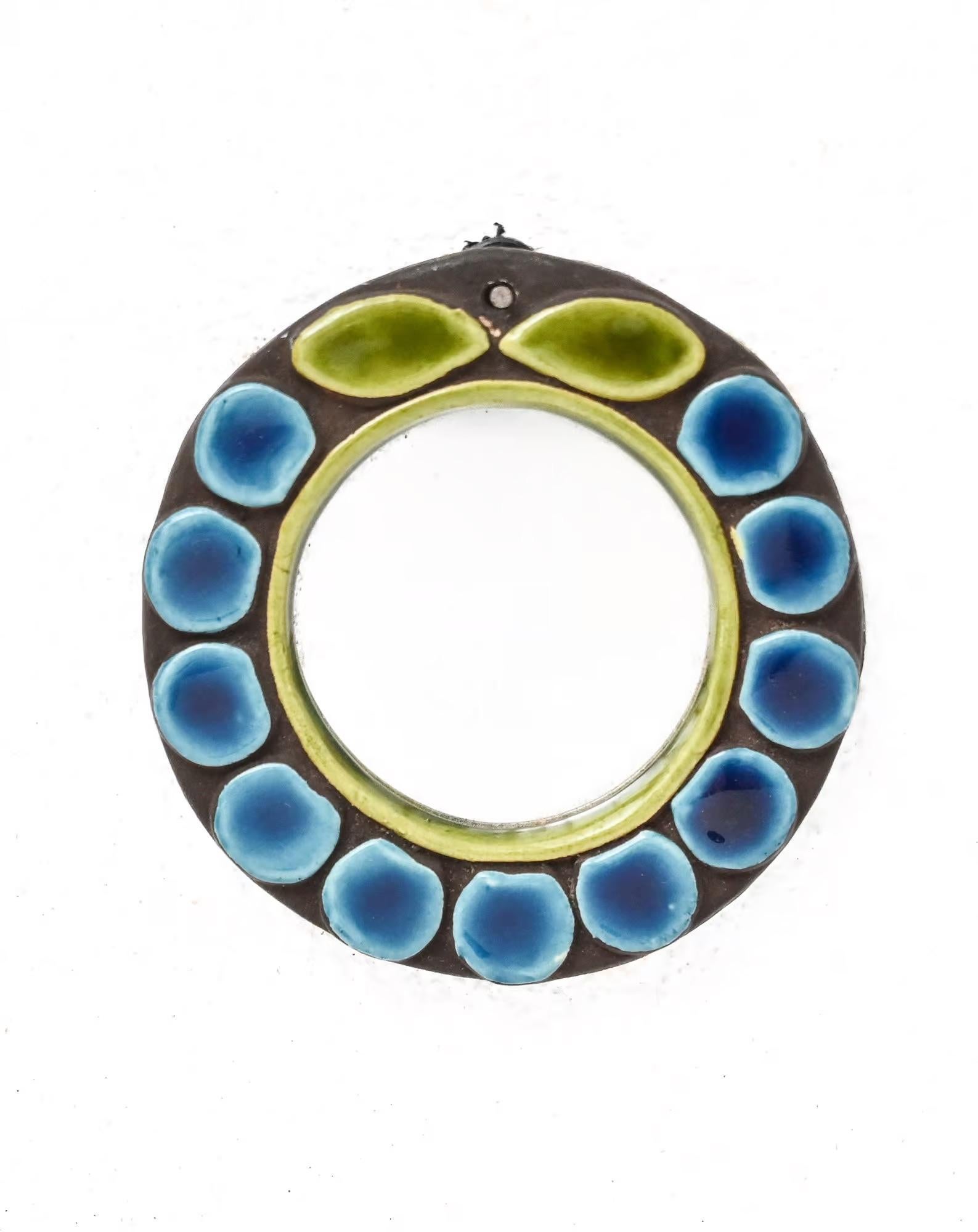 Small mid century Mithé Espelt “Fleur” pocket mirror c. 1960, embossed earthenware in shades of blue brown and green.(bead and brass chain missing)

Born in 1923, Mithé Espelt was a French ceramic artist based in the Camargue, at the gates of