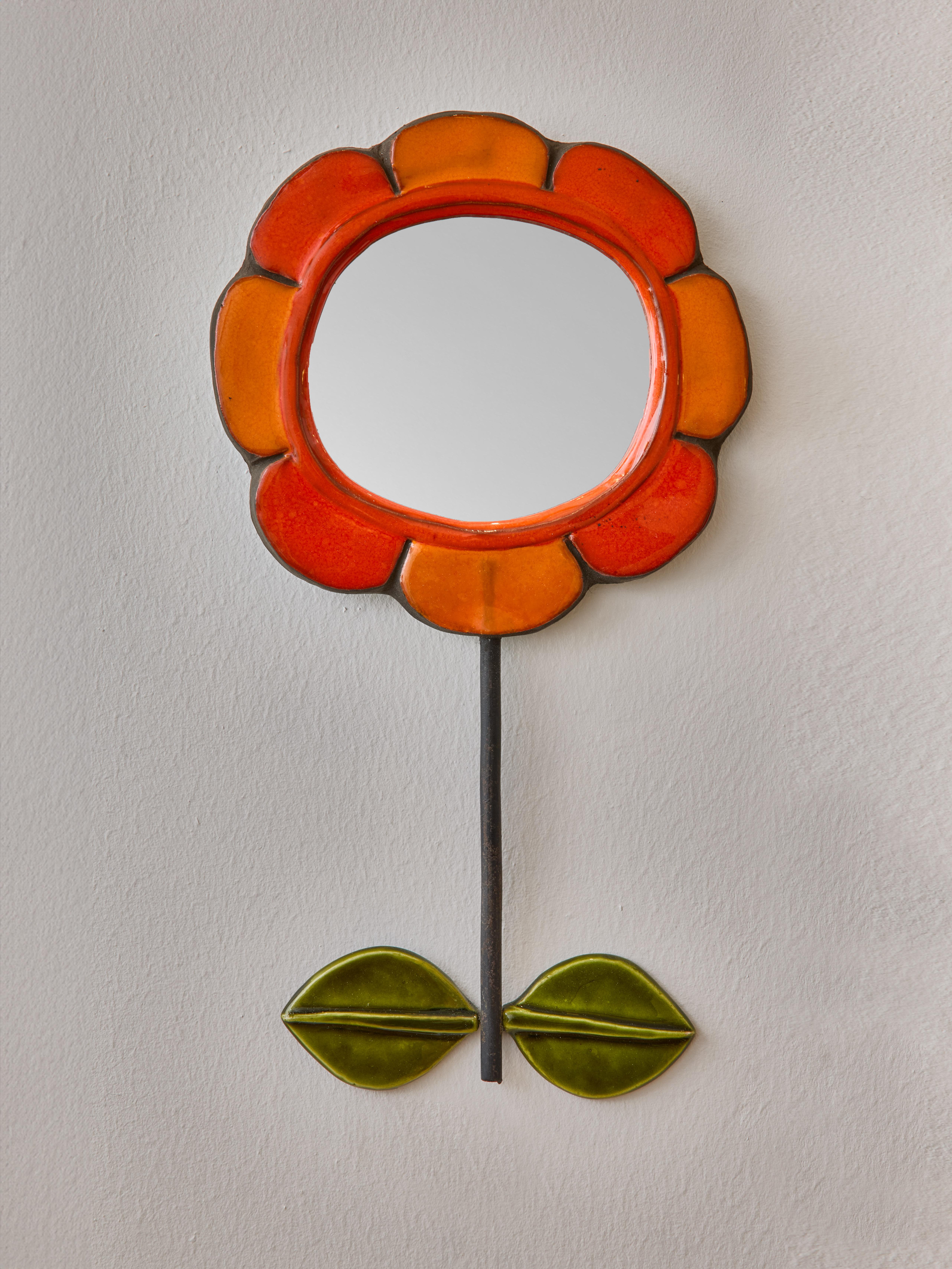 Miroir en céramique en forme de fleur avec des pétales orange. Tige verticale en métal sur laquelle sont fixées deux feuilles en céramique de couleur verte. Réalisé par Mithé Espelt.

 

Marie Thérèse Espelt, alias Mithé Espelt (1923-2020)

 

Née à