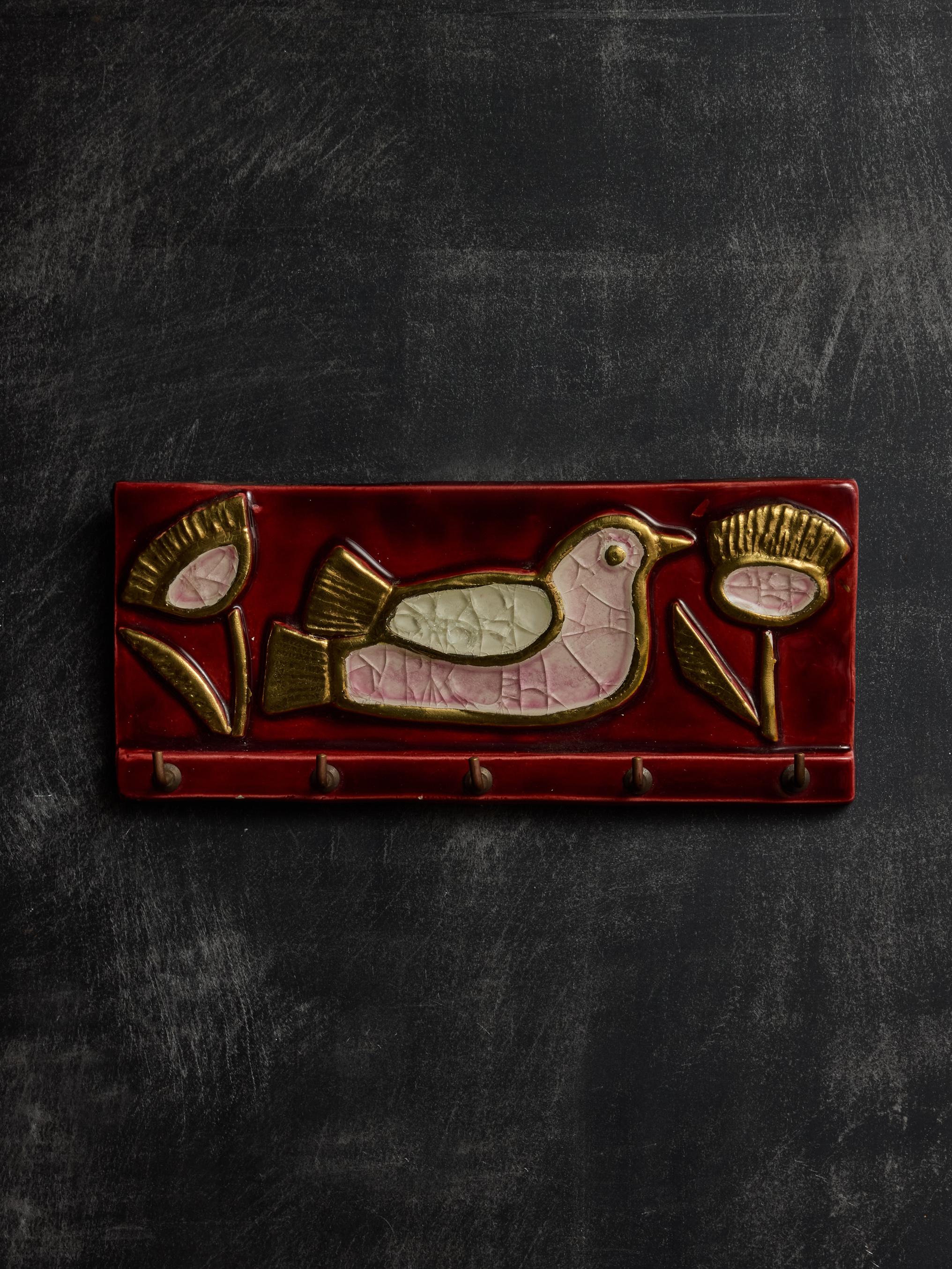 Surprising object by Mithe Espelt, this wall mounted key holder in dark red glazed ceramic with brass hooks, with decors of a bird and flowers.

 

Marie Thérèse Espelt, aka. Mithé Espelt (1923-2020)

 

Born in the town of Lunel, near Montpelier;