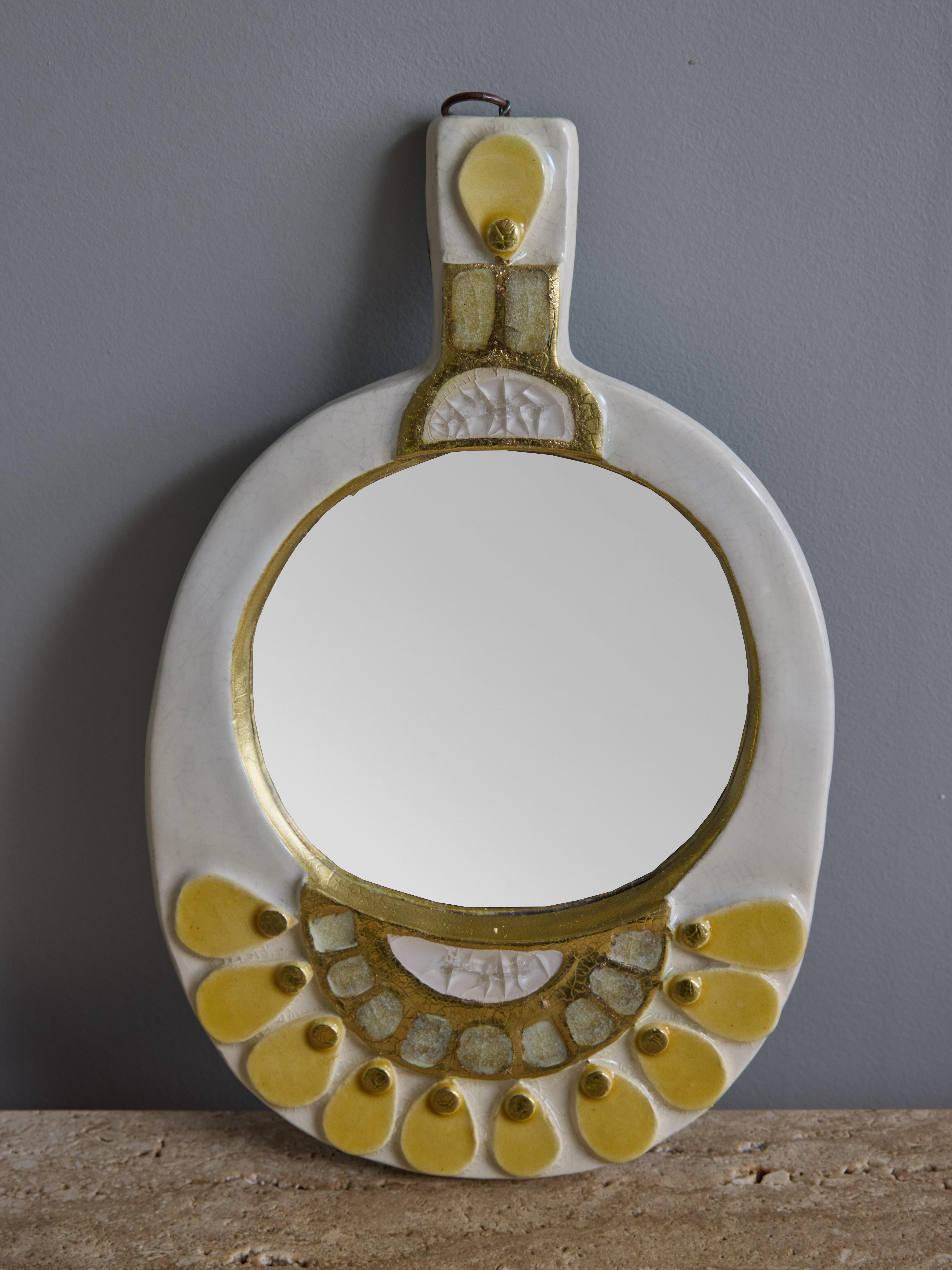 Miroir à main de l'artiste française Mithé Artistics, composé d'un cadre en céramique émaillée avec des décors en verre fondu entourant un miroir rond. Il est également doté d'un cerceau métallique à accrocher au mur.

Marie Thérèse Espelt, alias