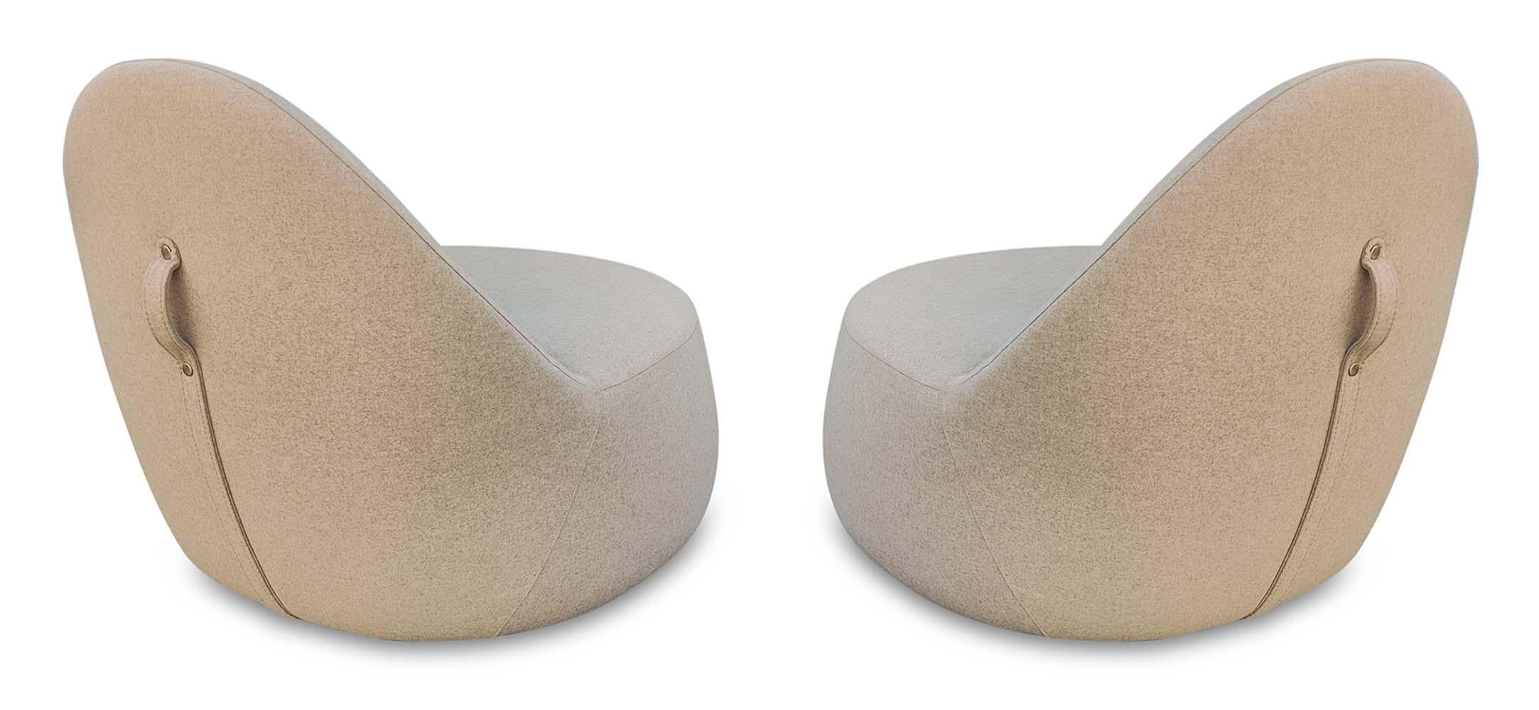This pair of elegant and space-age chairs was designed by Claudia and Harry Washington for production by Bernhardt Design. They are dressed in a sand color, and feature a strap on the back for increased handleability. The strap runs down the back of