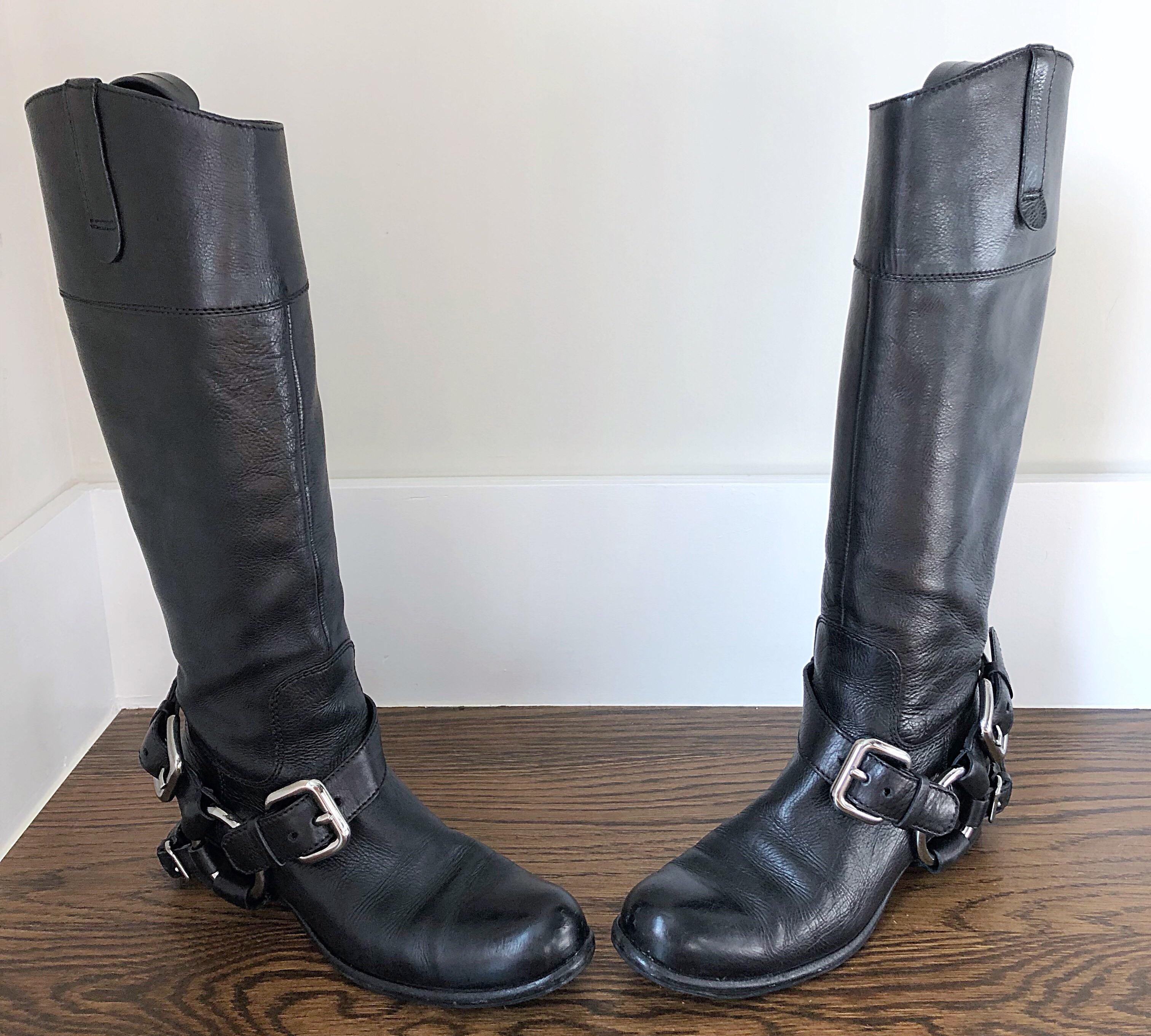 Chic late 90s MIU MIU black leather flat motorcycle boots with removable silver buckle harness. Comfortable, yet stylish and great for everyday wear. Zips up the inner calf. Can easily be dressed up or down. Great with jeans, a skirt, or a dress. In