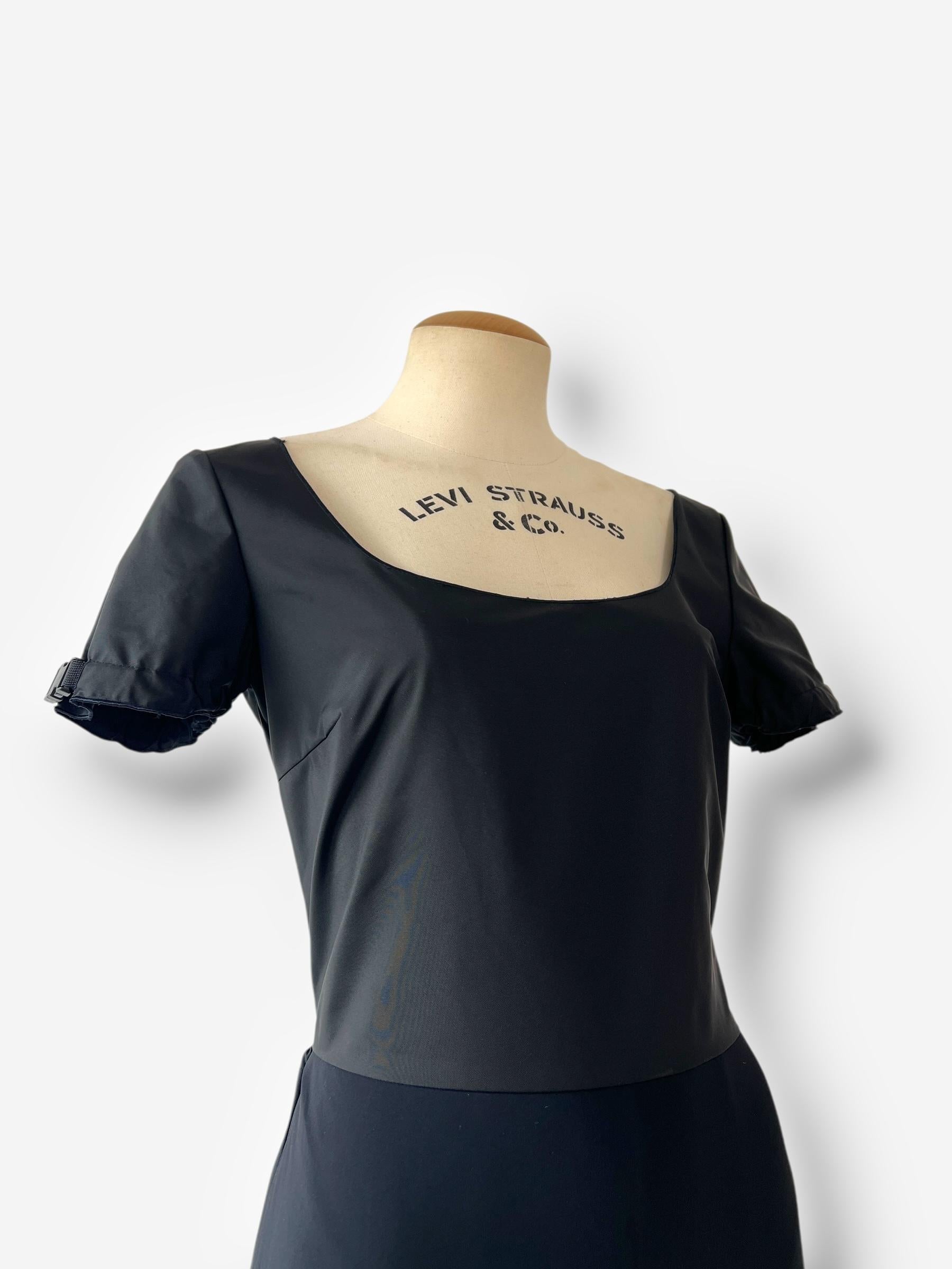 Abito nero, in nylon e scuba, con orlo in maglia a coste, dettagli con fibbie sulle maniche e vita stretta, disegnato da Miuccia Prada esattamente come visto sulla passerella di MIU MIU per l'autunno 1999. 

Condit: 7/10 orlo inferiore rassicurato e