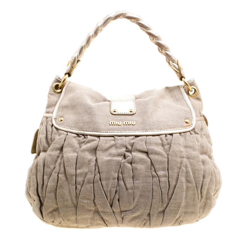 This Coffer hobo from the house of Miu Miu is designed in a versatile beige canvas body and detailed with gold-tone accents. It comes with a braided top handle and trimmed with leather. It comes fitted with a canvas lined interior and can easily