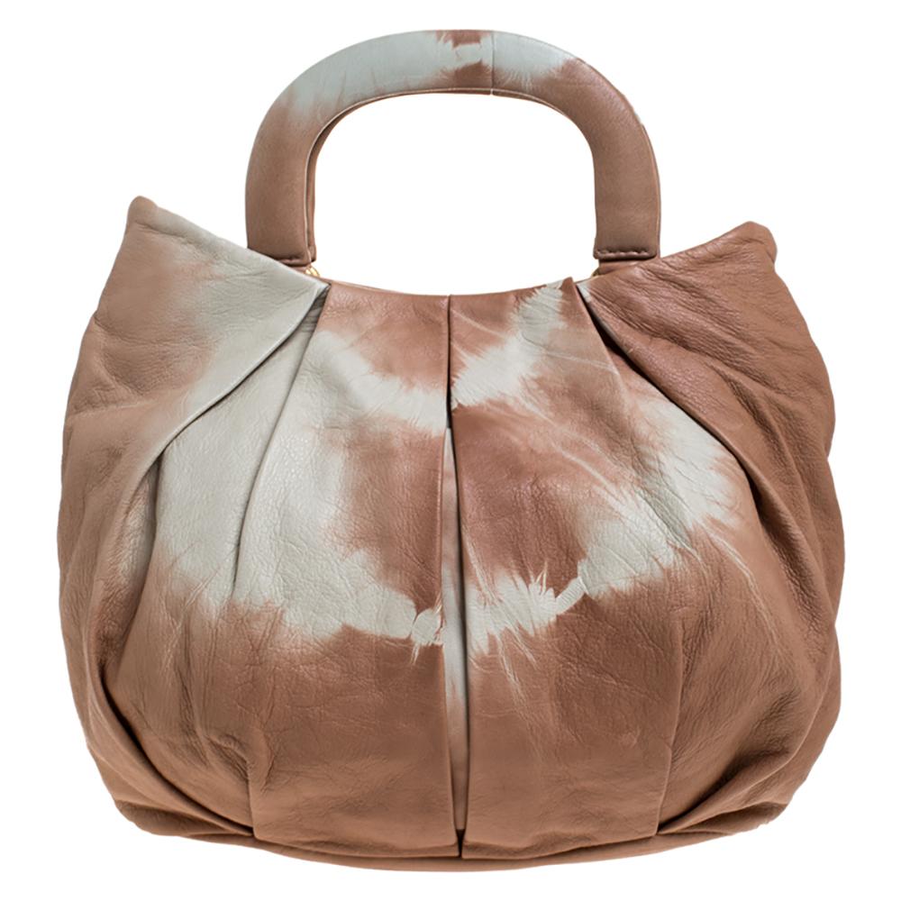 Miu Miu is known for its quality craftsmanship and designs. Designed with quality leather, this bag will make a statement every time you carry it. It flaunts a tie-dye exterior with beige & cream hues. It is styled with dual handles, brand logo on
