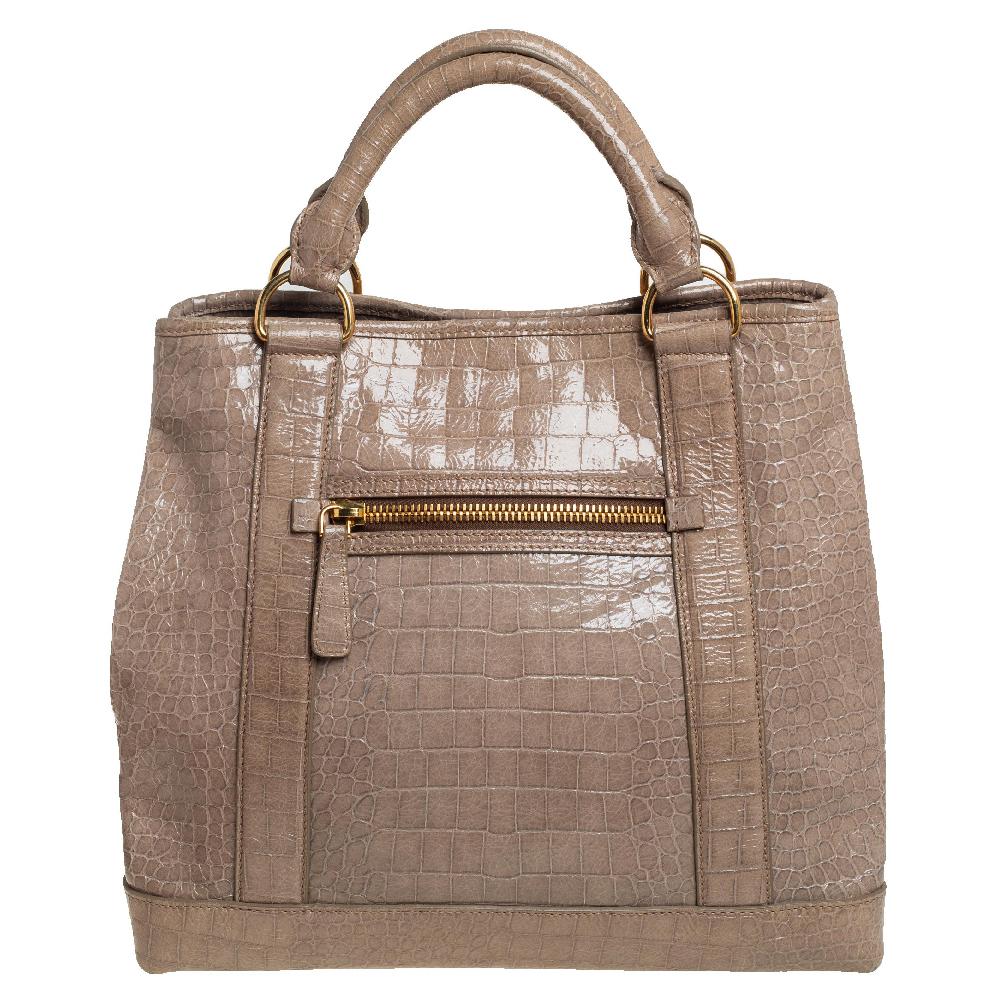 Stunning in appeal and simple in design, this tote by Miu Miu will be a valuable addition to your closet. Crafted from croc-embossed patent leather in a beige hue, the bag suspends from dual handles and an optional shoulder strap. The creation