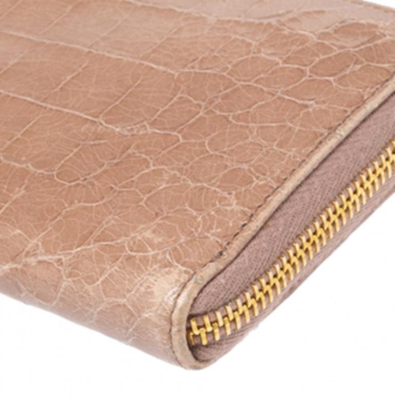 Crafted into an exquisite design, this wallet from Miu Miu is an important accessory. It has been made from croc-embossed patent leather and comes in a lovely shade of beige. It has the brand logo in the front and a zip closure that leads to a