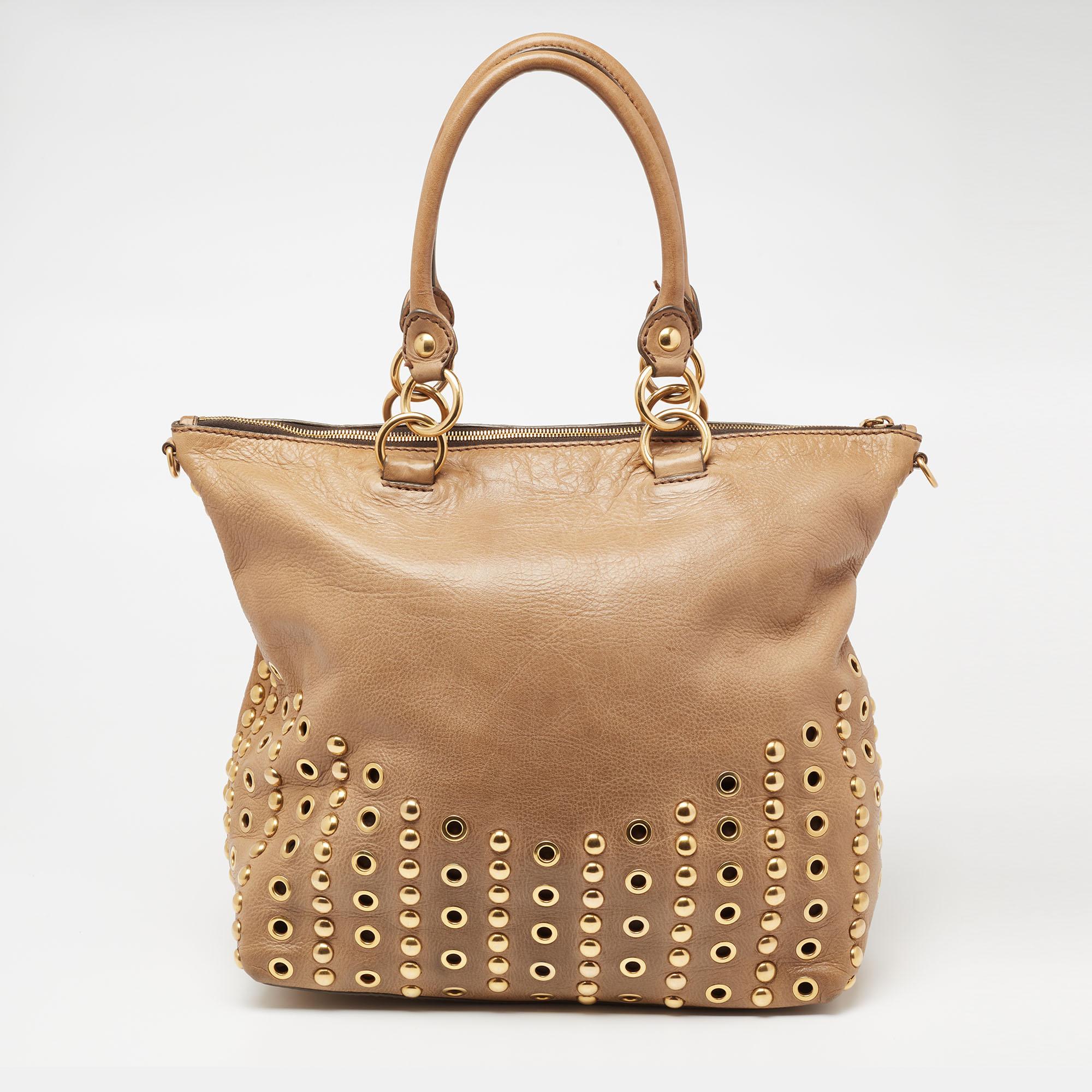 Perfect for work or travel, this Miu Miu tote is made of beige leather to be classy and durable. It has two top handles, an optional strap, grommet details, and a spacious lined interior.

Includes: Detachable Strap