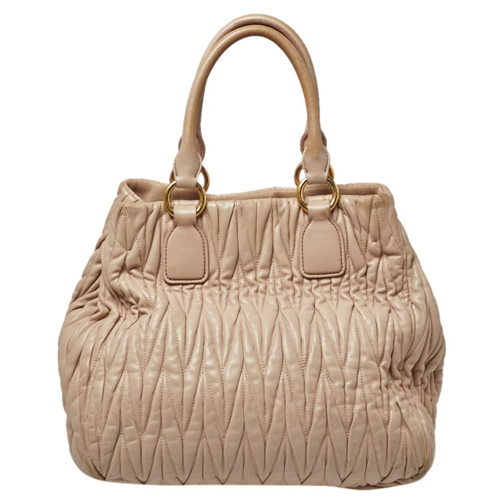 Miu Miu brings us this gorgeous bag that has been crafted from leather and designed using the Matelasse technique. It has a dreamy beige hue, a spacious satin interior capable of carrying your essentials, and a gold-tone brand label on the front.