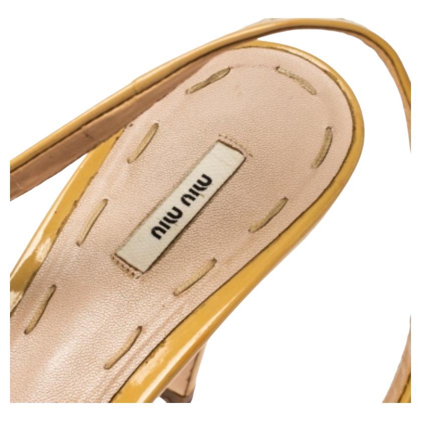 Holen Sie sich Ihren idealen Begleiter für legere oder formelle Anlässe aus dem Modehaus Miu Miu. Sie sind aus beigem Lackleder gefertigt und verfügen über eine Peep-Toe-Zehe, eine kontrastierende schwarze Schleife auf dem Vorderblatt und