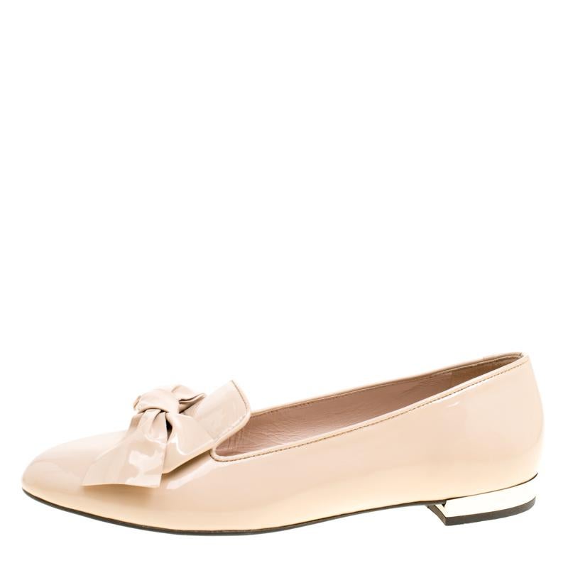 An epitome of comfort and class, these smoking slippers from Miu Miu are designed to add a touch of sophistication to your style. Styled with lovely bows on the uppers, these beige slippers are crafted from patent leather and the heels are detailed