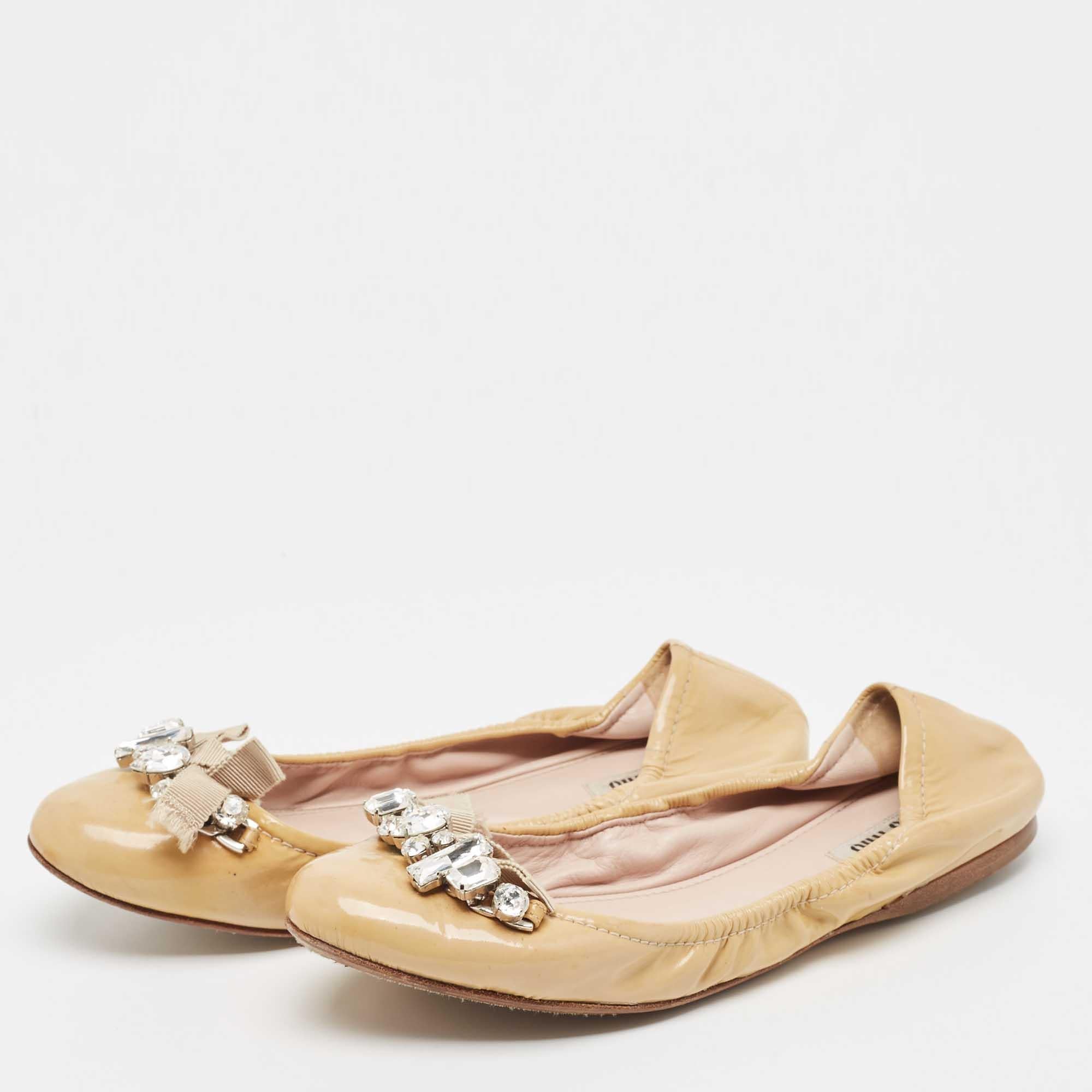 Creadas por Miu Miu, estas bailarinas son un estilo básico que toda colección de zapatos necesita. Fabricados en charol, los zapatos están realzados con cristales en el exterior. 