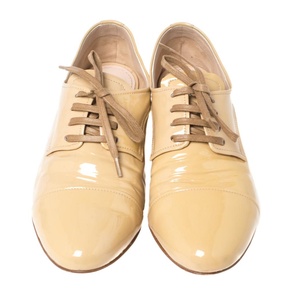 Glossy beige, simple laces, and crystal-embellished heels lend this pair a luxurious look. Designed by Miu Miu, the patent leather derby shoes will offer you the right amount of shine and comfort.

Includes: Original Dustbag