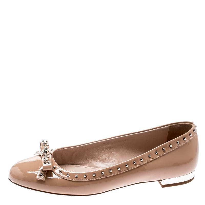 Smart and chic, break the monotony with these beige flats from Miu Miu. Crafted from patent leather, they come with leather insoles, stud embellishments and bows on the vamps. Exhibit your impressive styling sense when you don this pair.

Includes: