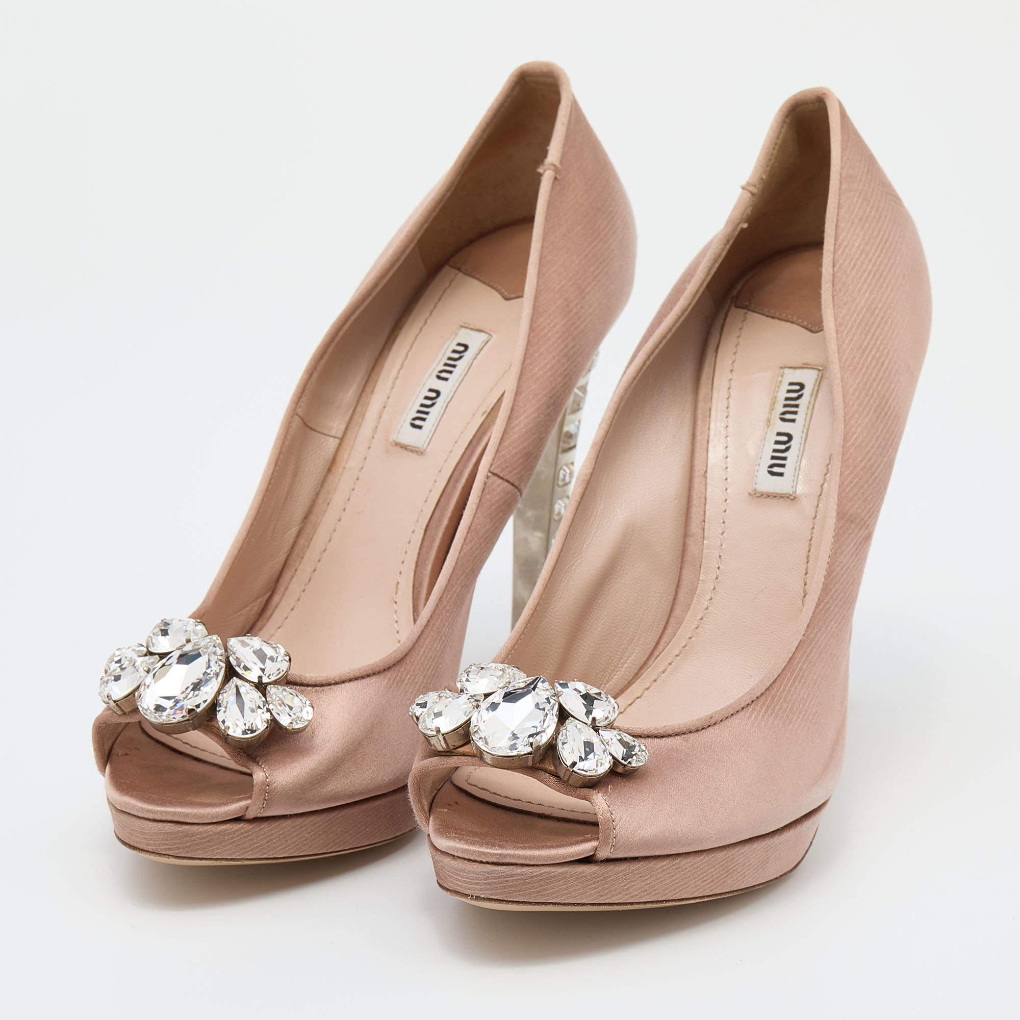 Make a dazzling statement with these gorgeous platform pumps from Miu Miu! The beige pumps are crafted from satin and feature peep-toes with crystal embellishments, platforms, and crystal-studded 12 cm heels.

