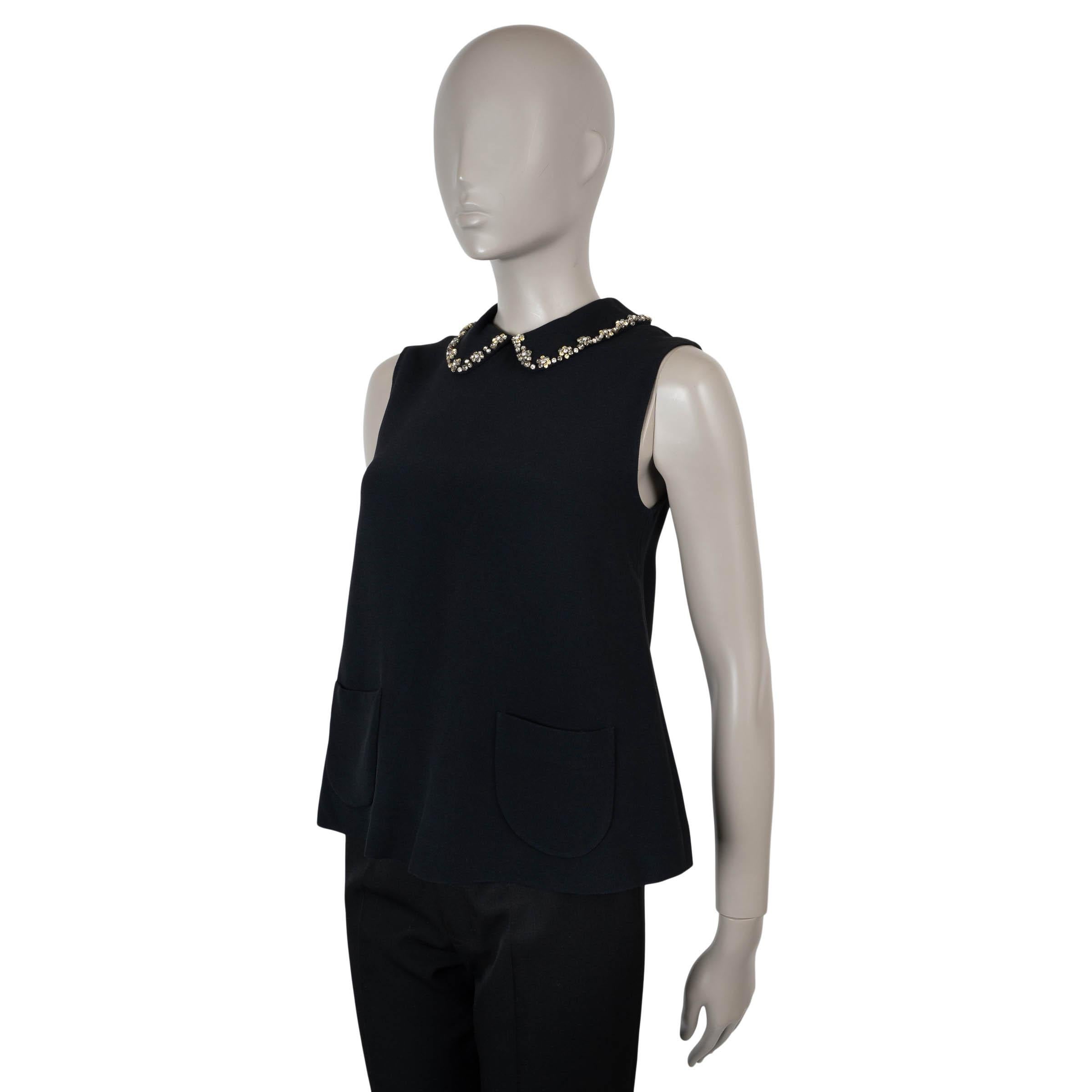 Cette blouse Miu Miu 100 % authentique en acétate (53 %) et viscose (47 %) noirs incarne une féminité raffinée. Conçue avec une silhouette évasée et sans manches, elle est rehaussée d'un col Peters garni de fleurs et orné de cristaux de verre