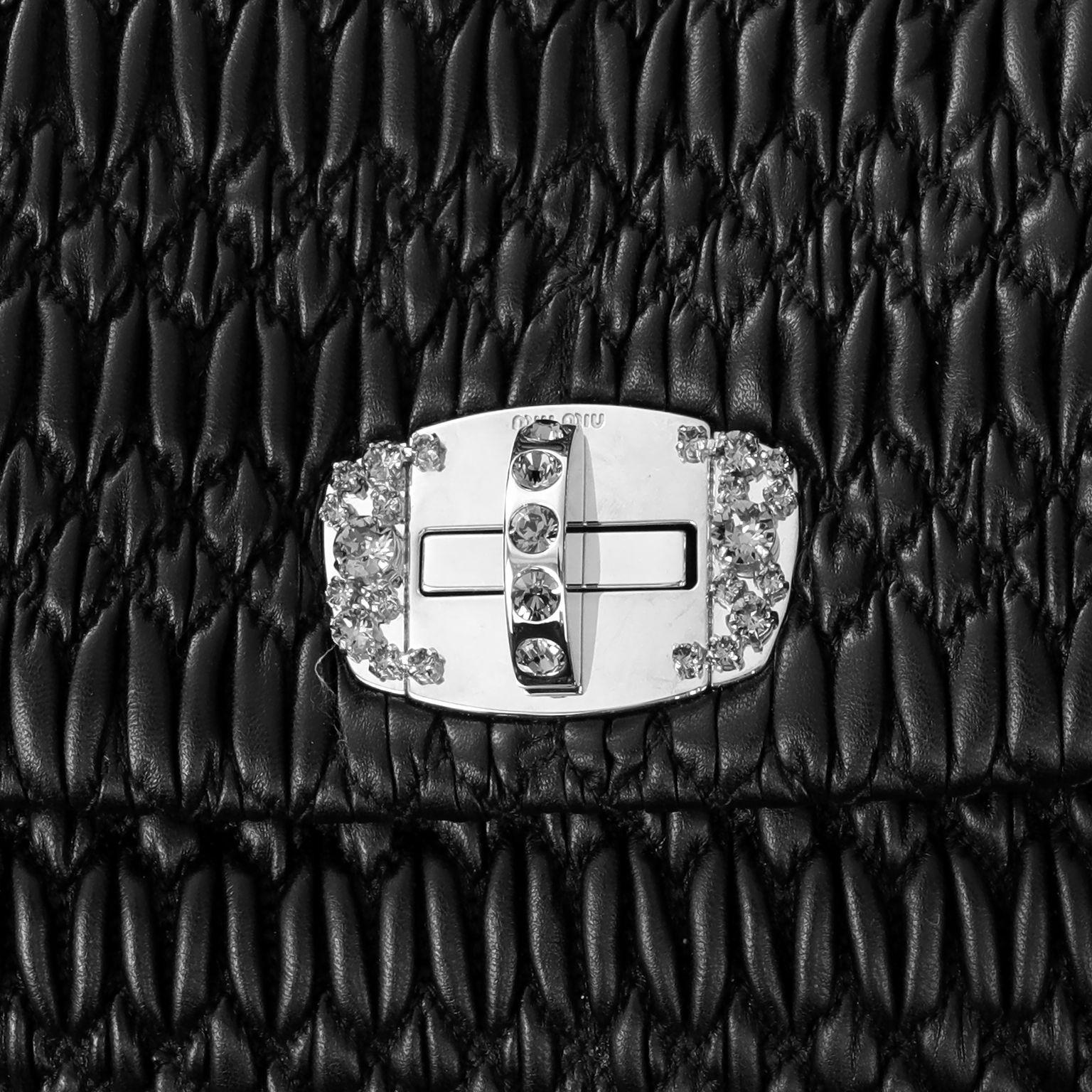 Ce sac Miu Miu Black Crystal Condit est en parfait état.  Ce modèle emblématique se compose de cuir Nappa matelassé en relief noir et d'une fermeture à verrou tournant en argent et en cristal.  Peut être porté avec la lanière de cuir amovible ou la