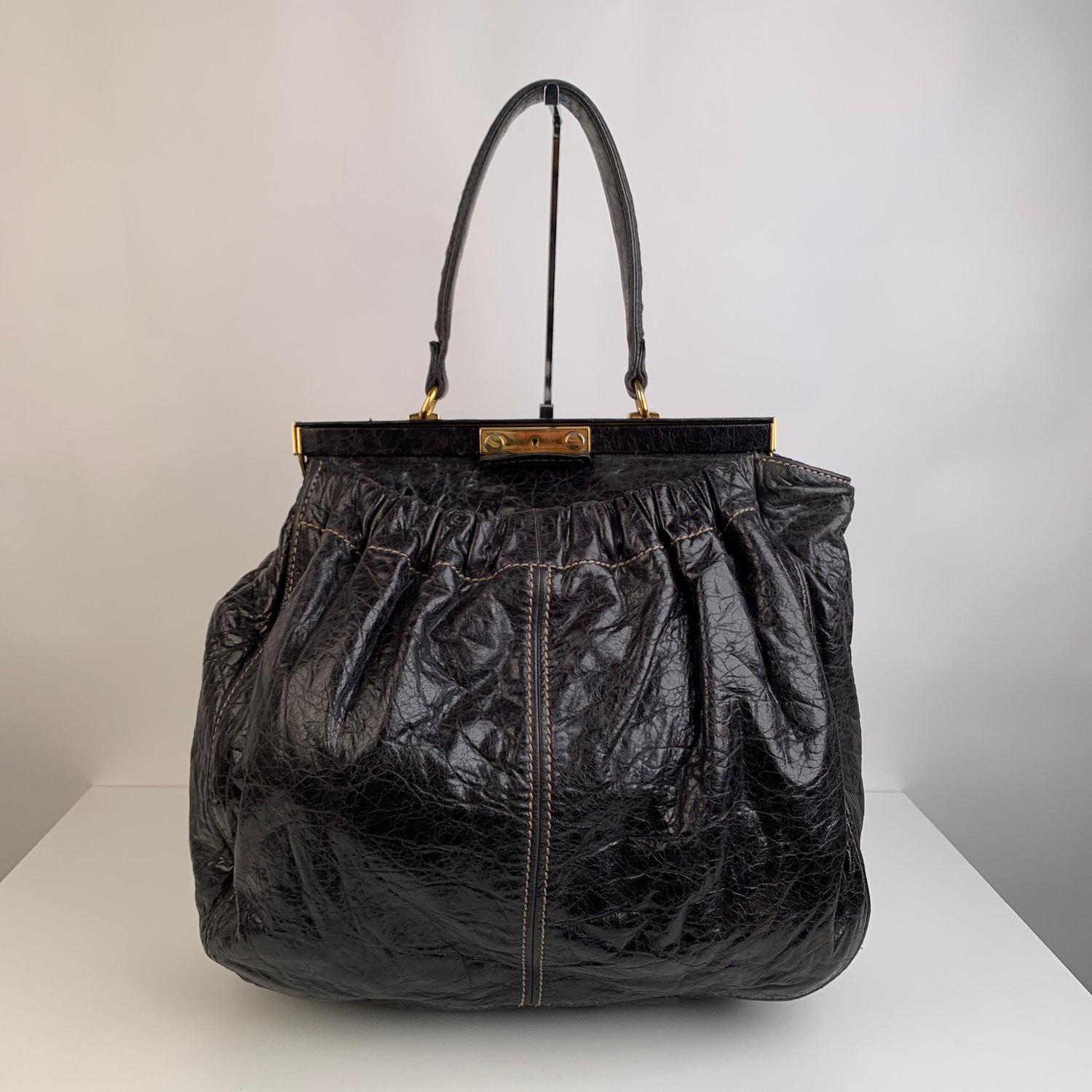 Black leather Miu Miu large tote bag with distressed finish. It features a framed top with key-lock closure (keys and key clochette are missing). Gold-tone hardware and top carry handle. 2 large open pockets on the exterior (one on the front and one