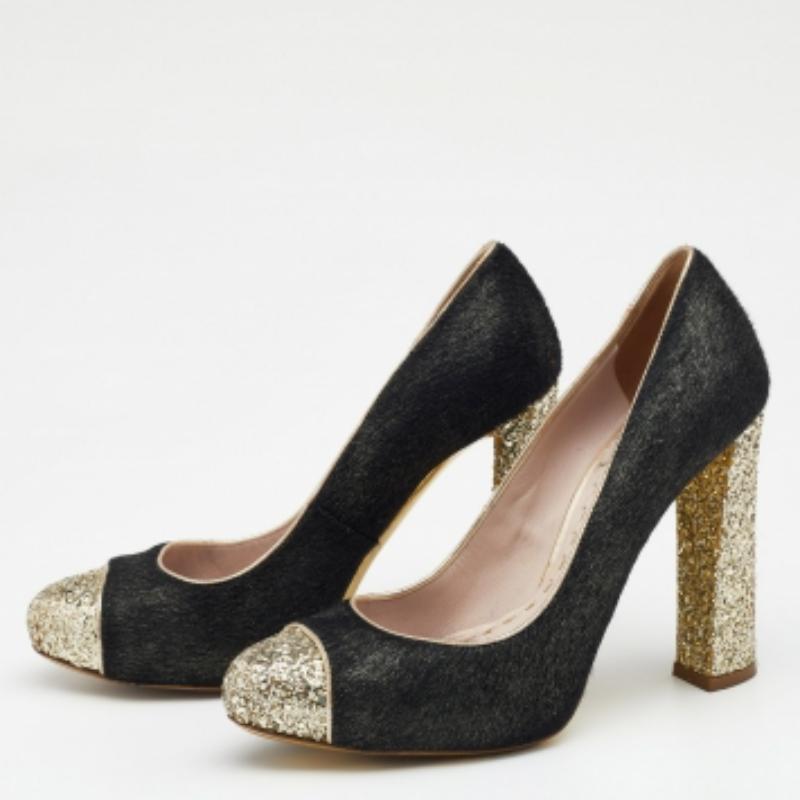 Grab these gorgeous pumps from the House of Miu Miu, and walk confidently with elegant grace! Fashioned in black-gold calf hair and glitter, these pumps are enhanced with cap toes, block heels, and a slip-on feature. These pumps will pair well with